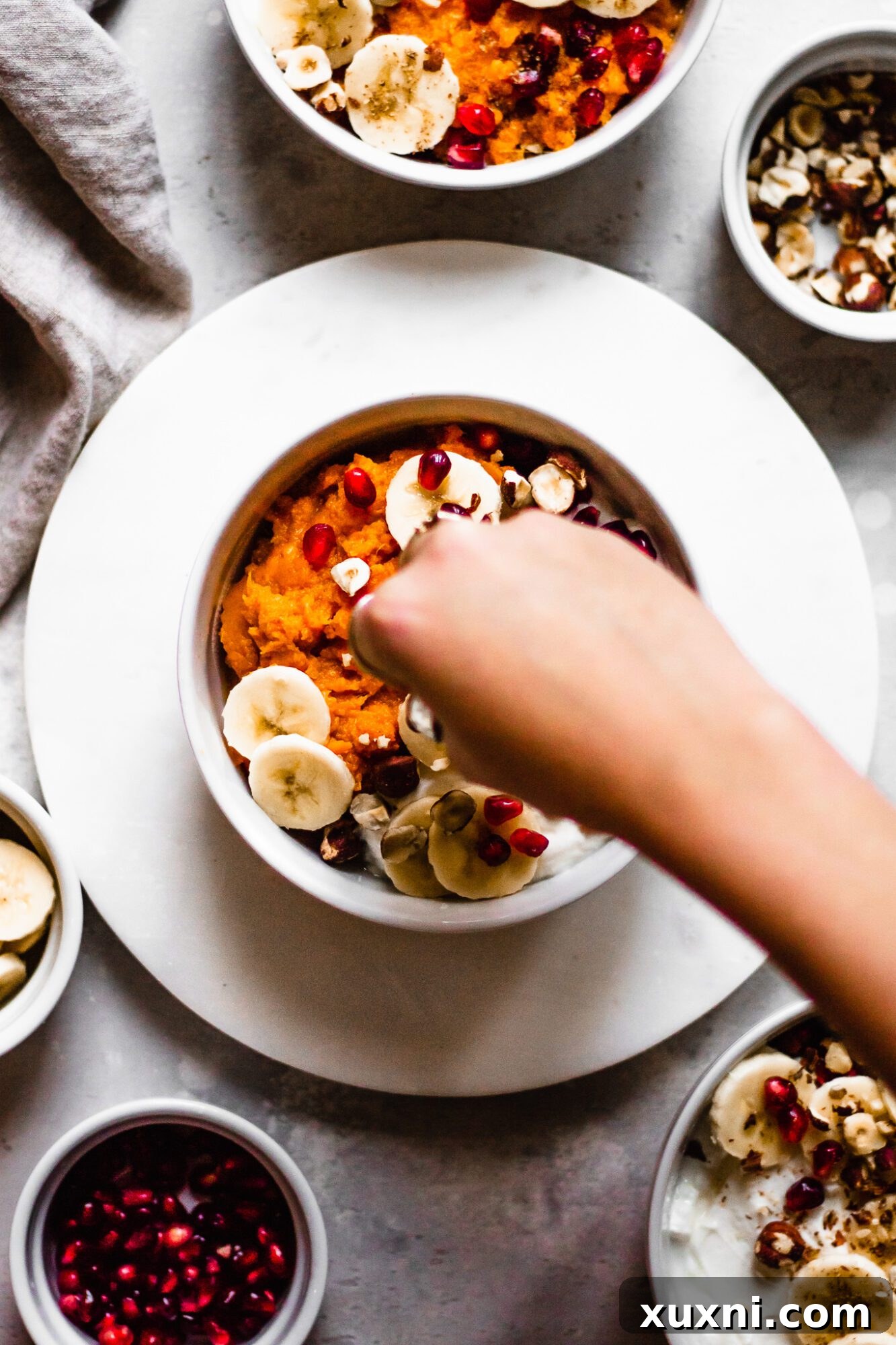 hand toppings nuts and seeds onto sweet potato bowls