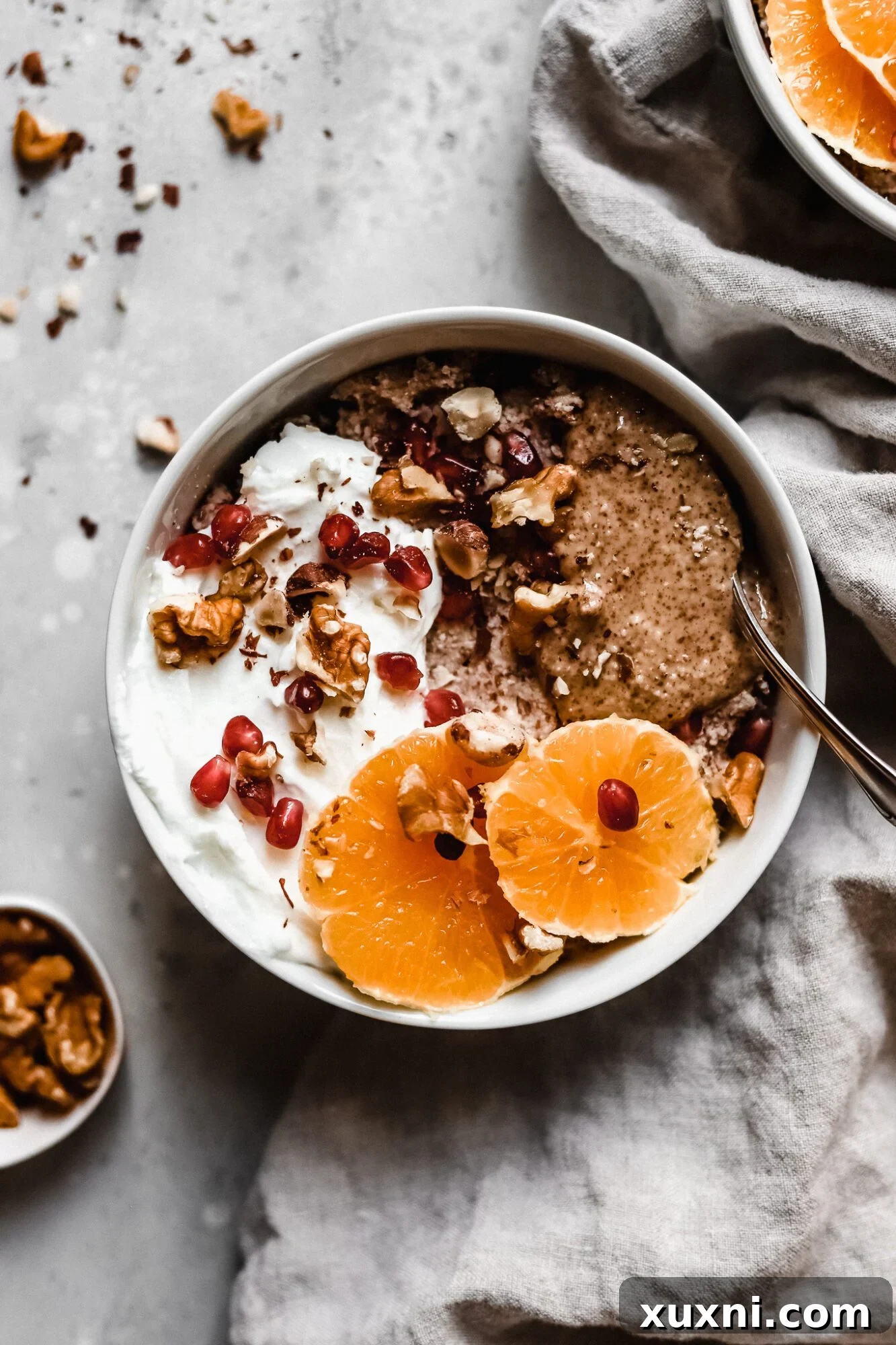A vibrant bowl of Whole30 oatmeal, garnished with fresh orange slices, cinnamon, and walnuts.