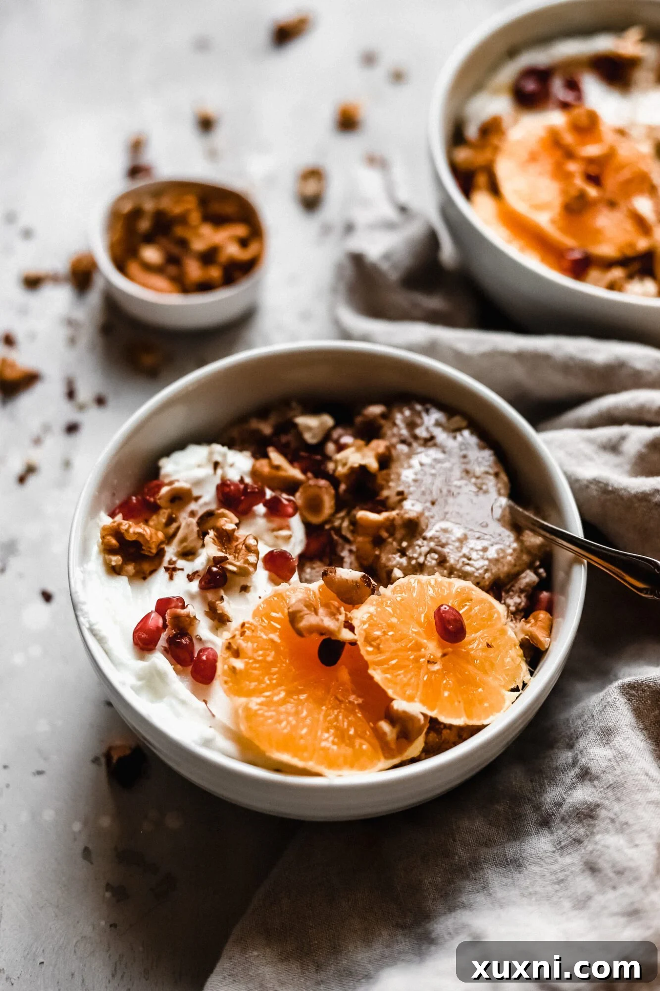 Two close-up bowls of grain-free hot cereal with fresh fruit and nuts.