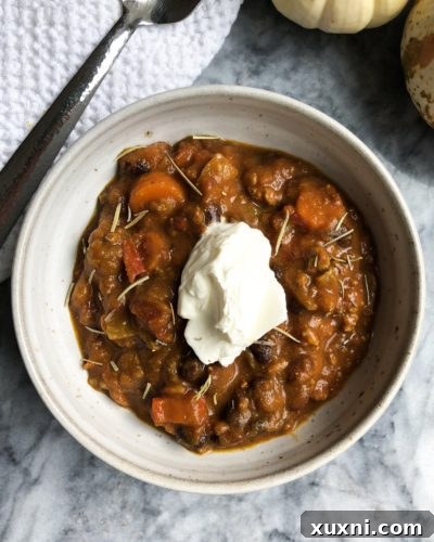 A comforting bowl of pumpkin chili, garnished with fresh herbs, ready to be enjoyed.