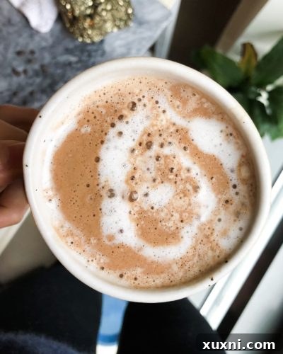 Close-up of a festive peppermint hot chocolate mug adorned with a candy cane, evoking holiday cheer.