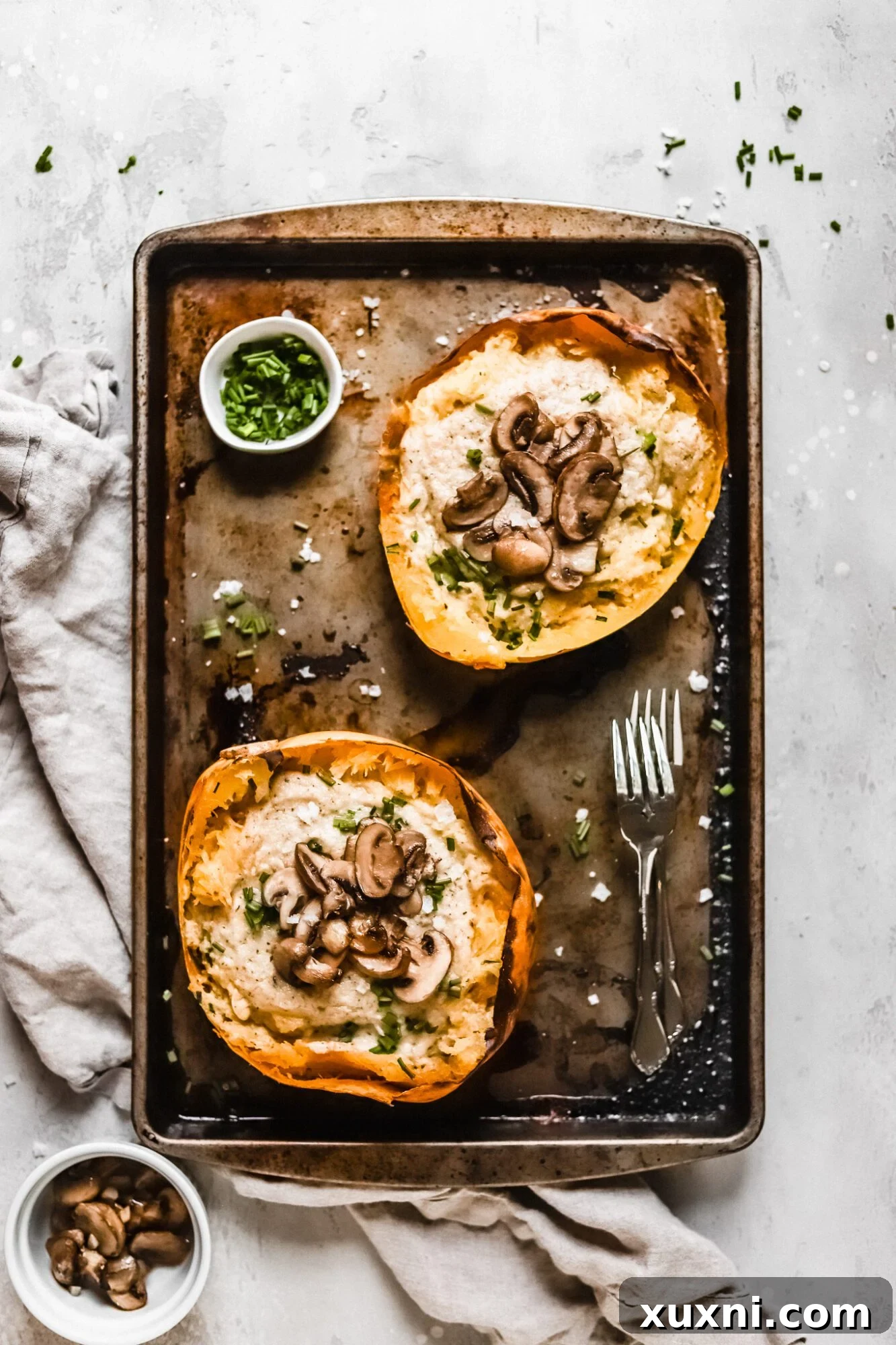 Spaghetti squash boats neatly arranged on a baking dish, showcasing their generous filling of vegan Alfredo sauce and mushrooms.