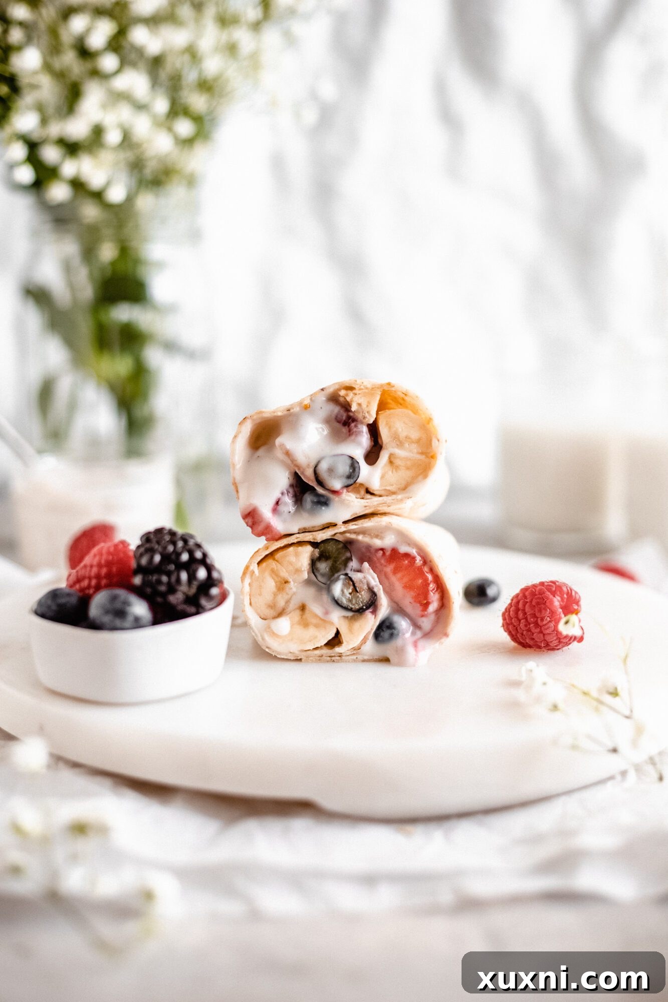 A sweet vegan breakfast burrito filled with yogurt and berries, sliced to show the creamy filling