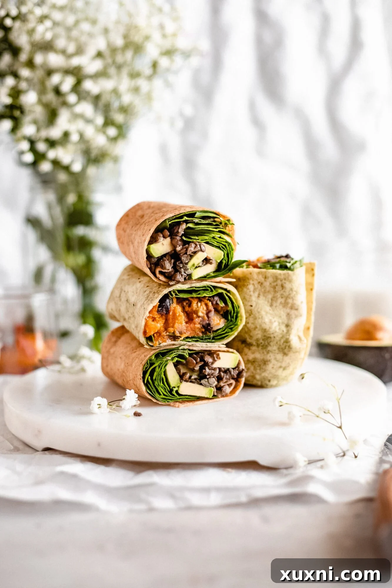 Three types of vegan breakfast burritos, stacked and showing their savory fillings