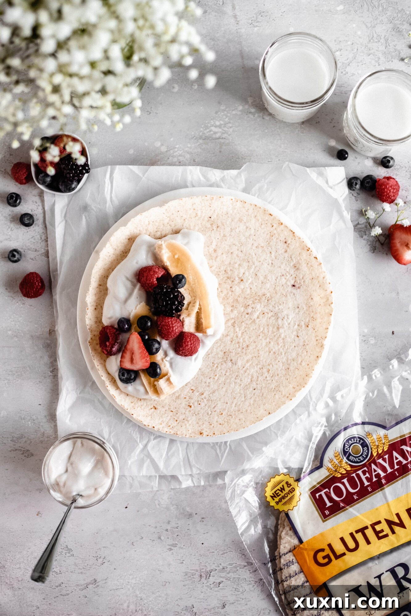 A vegan breakfast burrito being assembled on a flat surface, showing the first fold