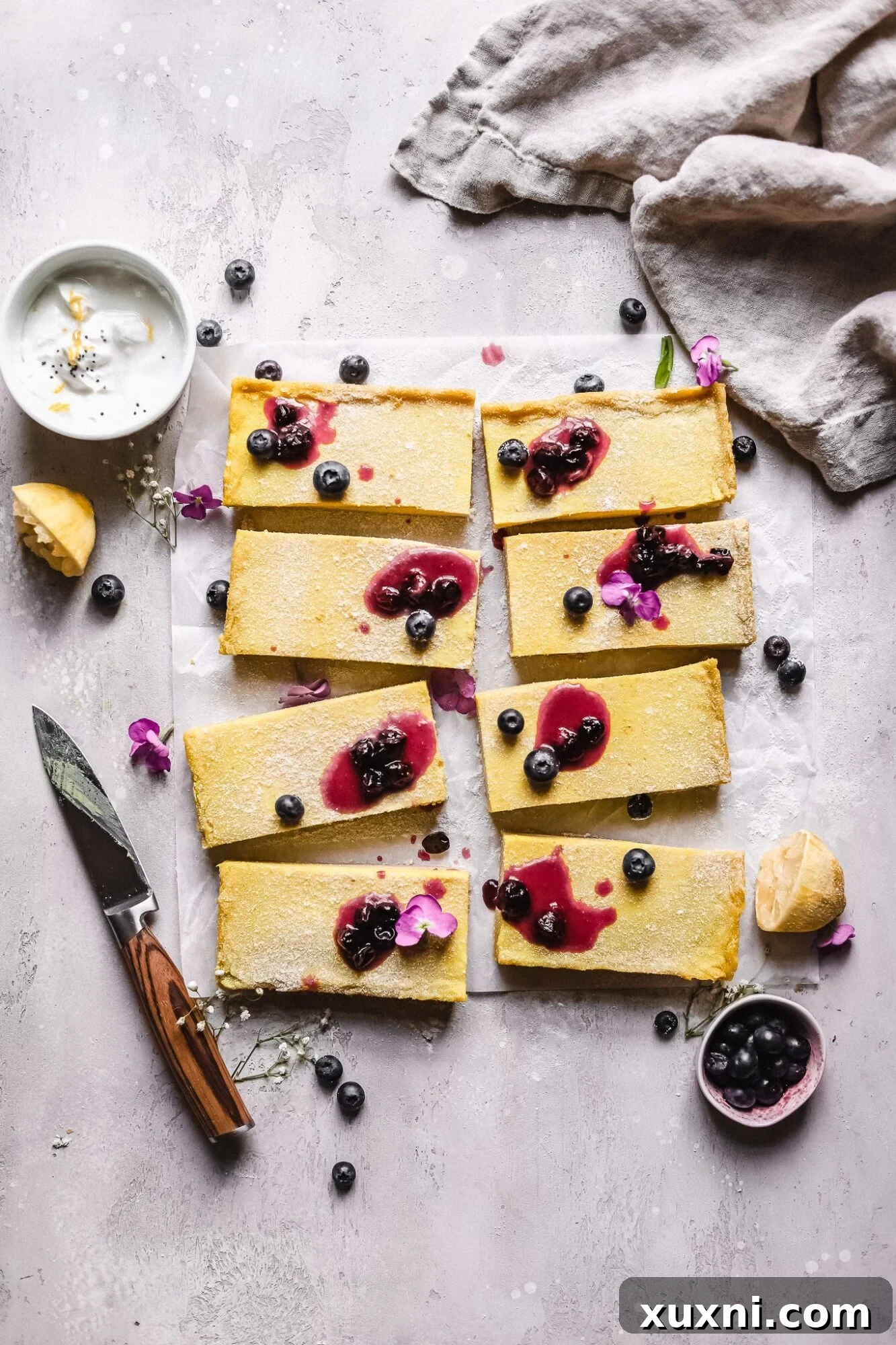 sliced Paleo vegan lemon bars with blueberry jam on top with a knife next to it