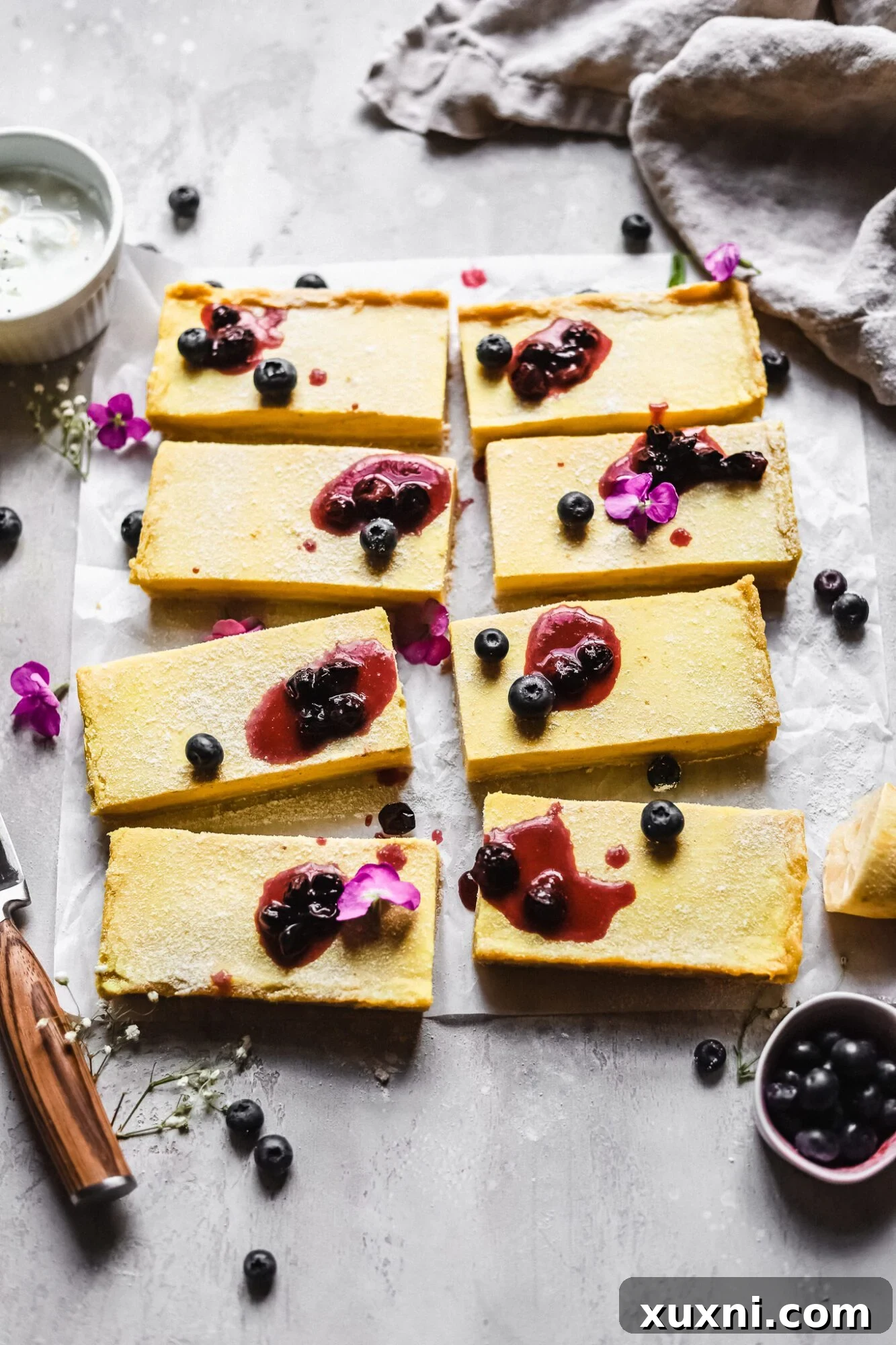 3/4 shot of lemon bars with blueberries and warmed blueberry jam on top