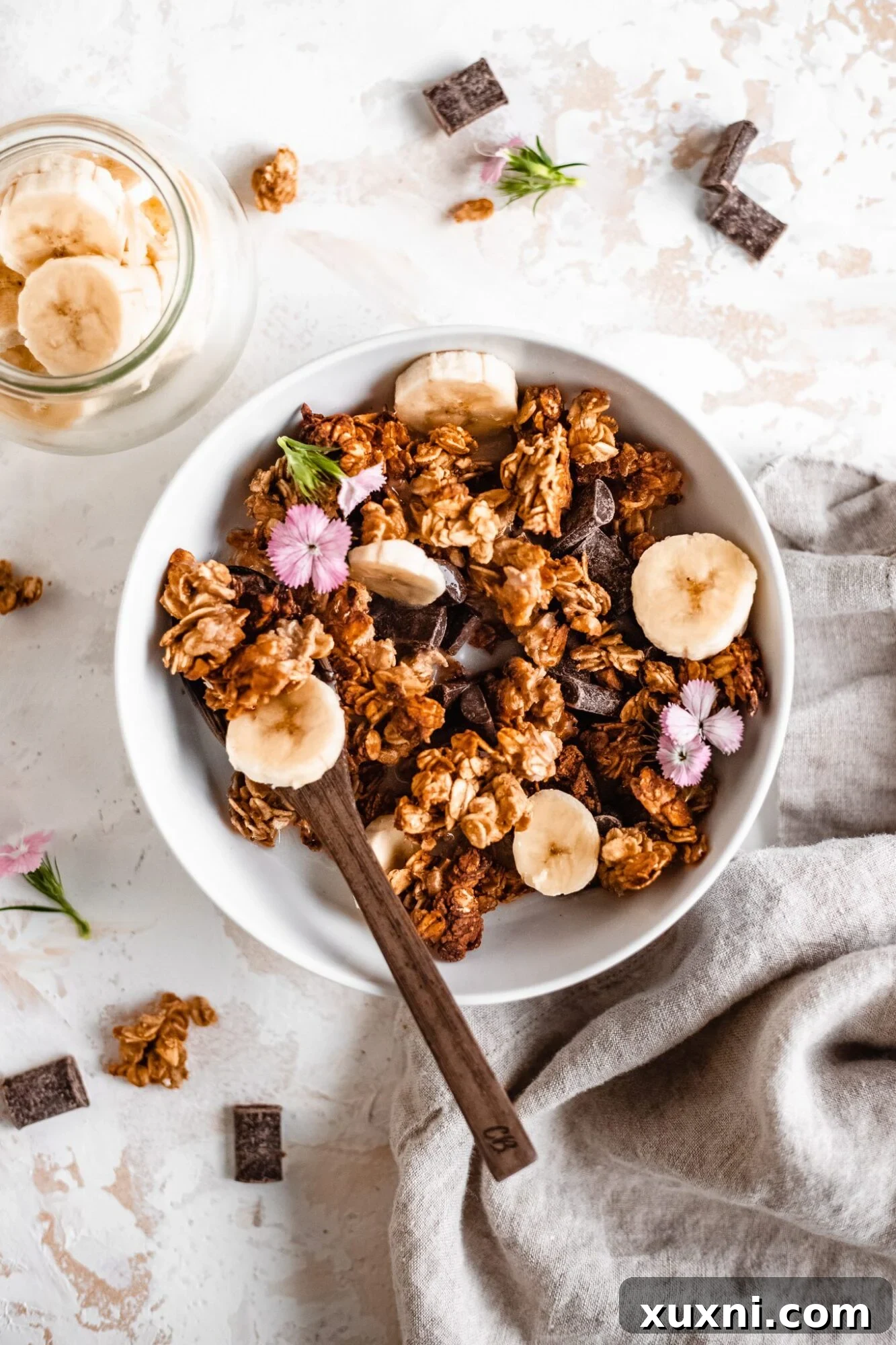 A vibrant bowl of homemade oil-free banana bread granola, generously studded with chunks of banana and ready to be enjoyed as a healthy breakfast.