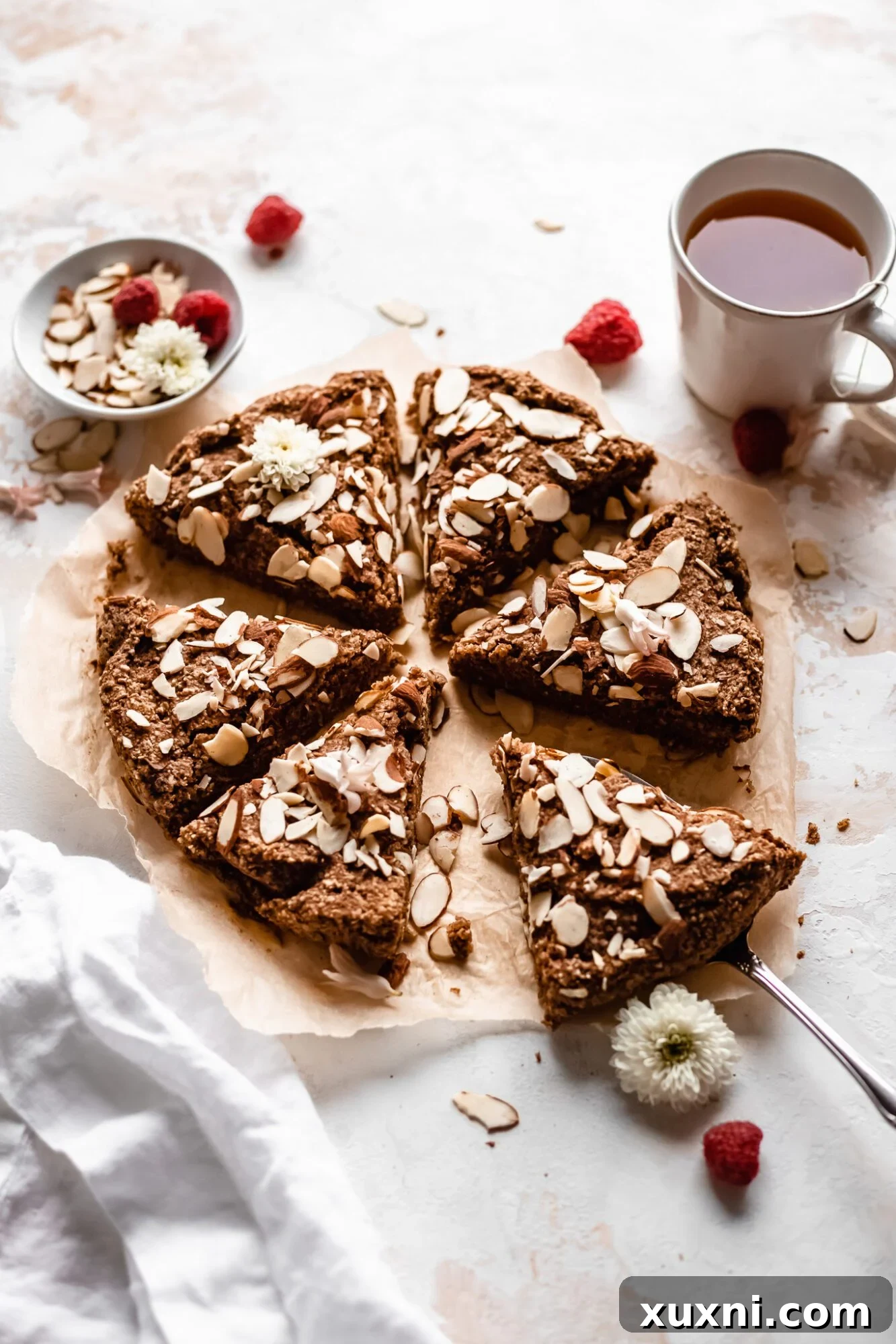 A slice of almond cake being gently pulled from the freshly baked cake