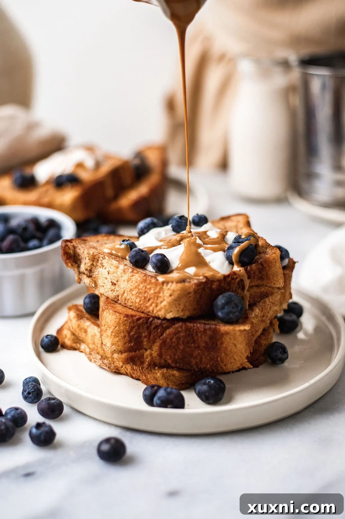 stack of vegan French toast with a drizzle of peanut butter and blueberries on a plate