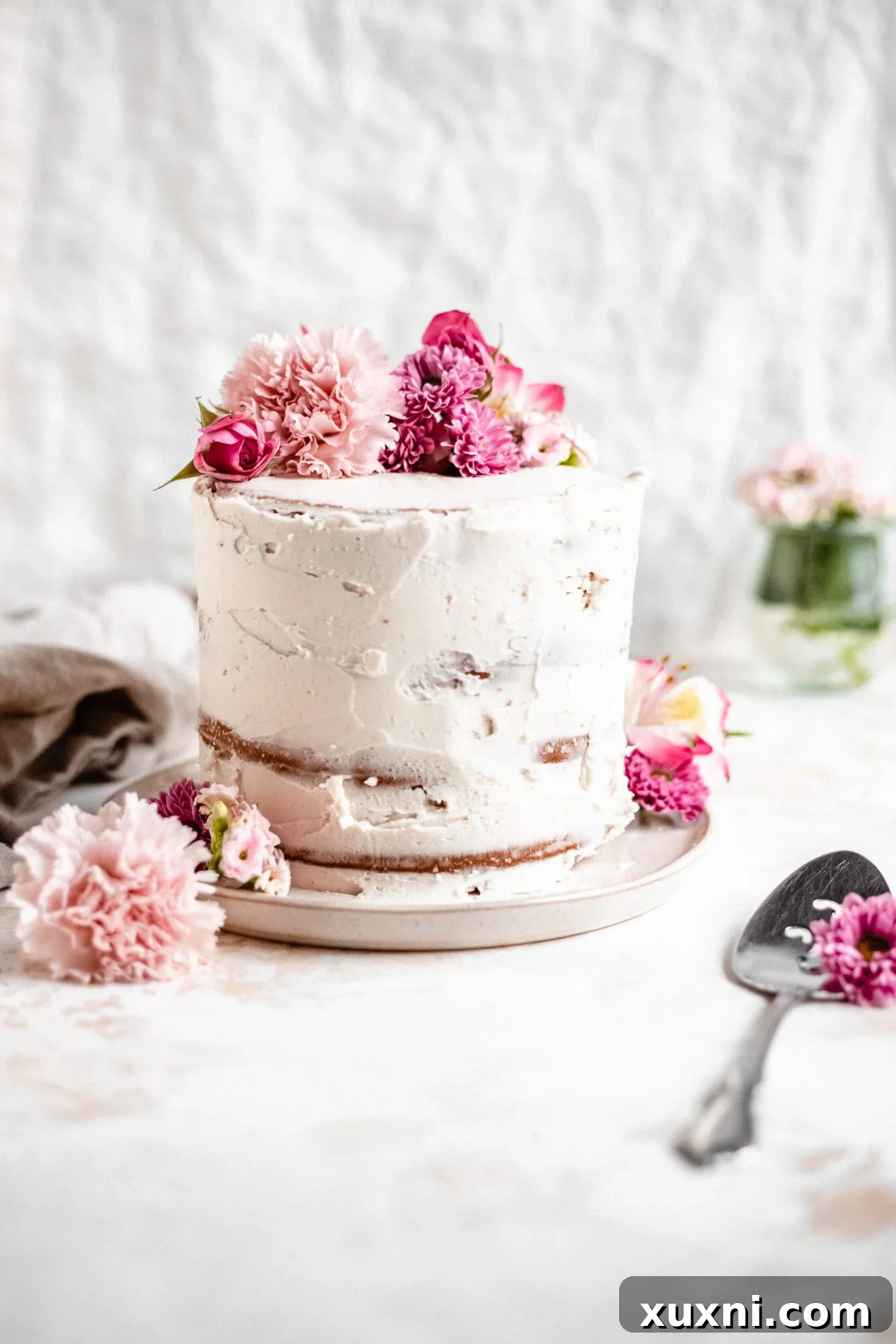 Close-up of a beautifully decorated vegan cake with fresh flowers, showcasing its light and festive spring appeal.