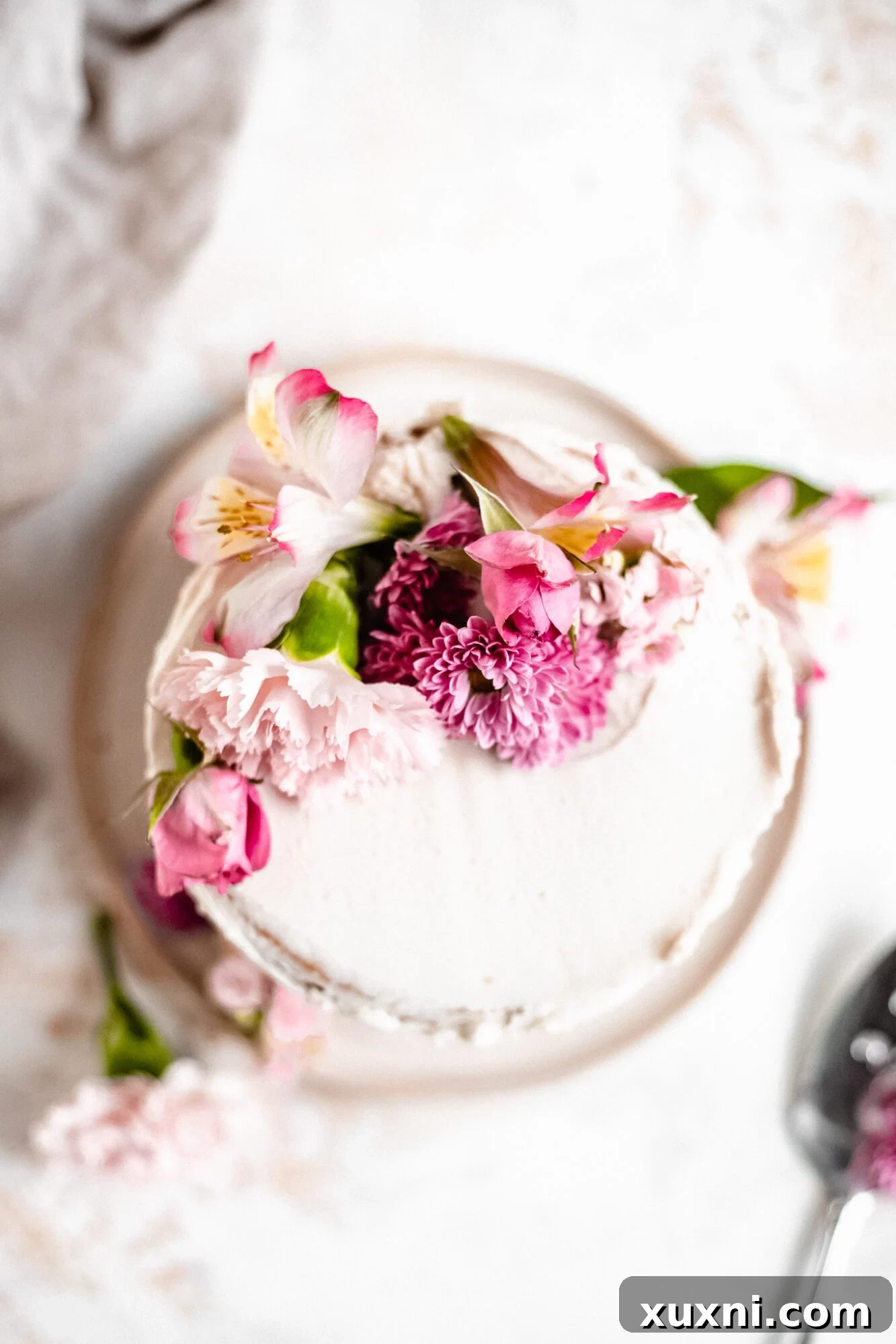 An overhead shot of the vegan pastel layer cake, showcasing its delicate frosting and simple, elegant decoration.