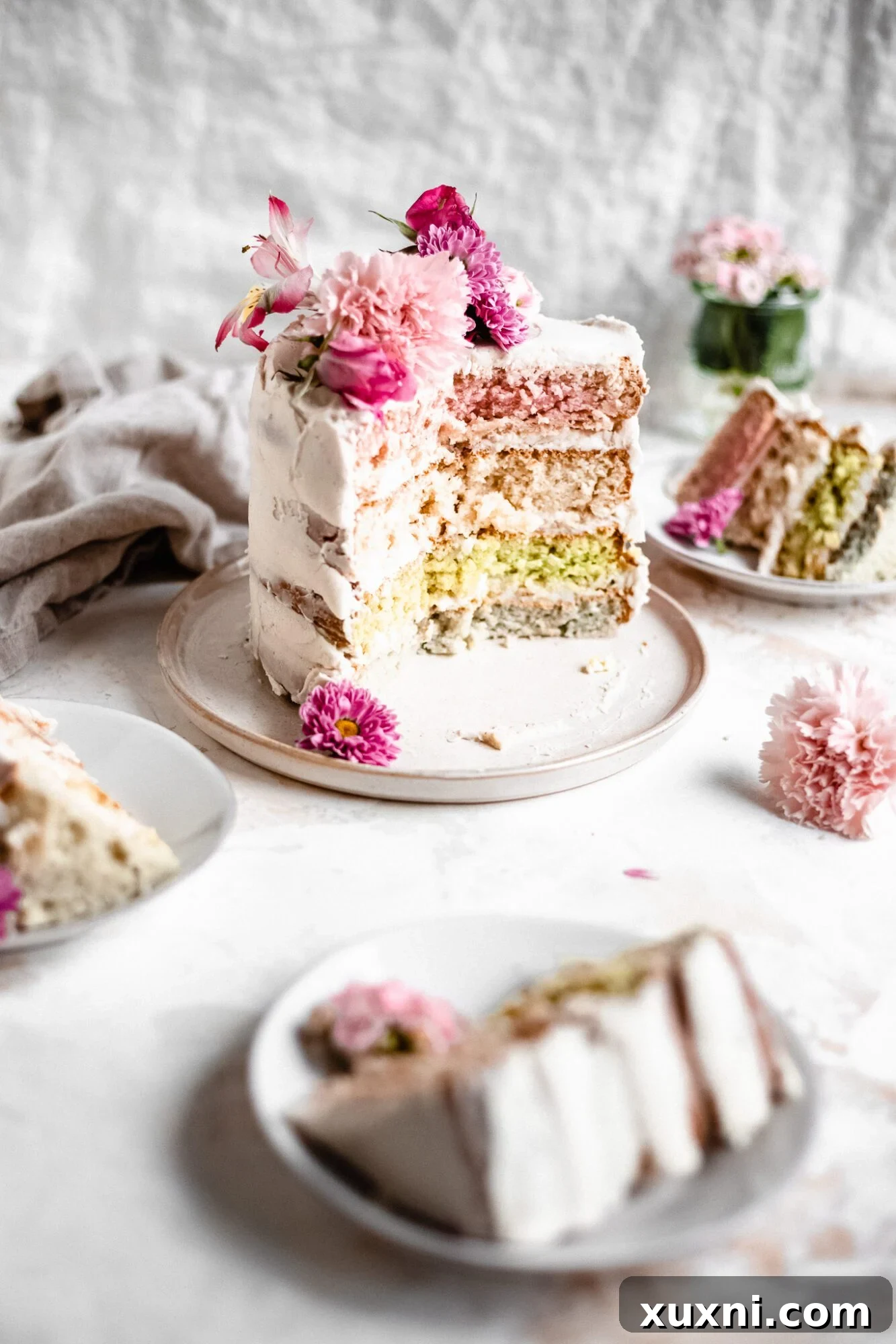 Several slices of vegan pastel layer cake on small plates, highlighting the distinct colorful layers.
