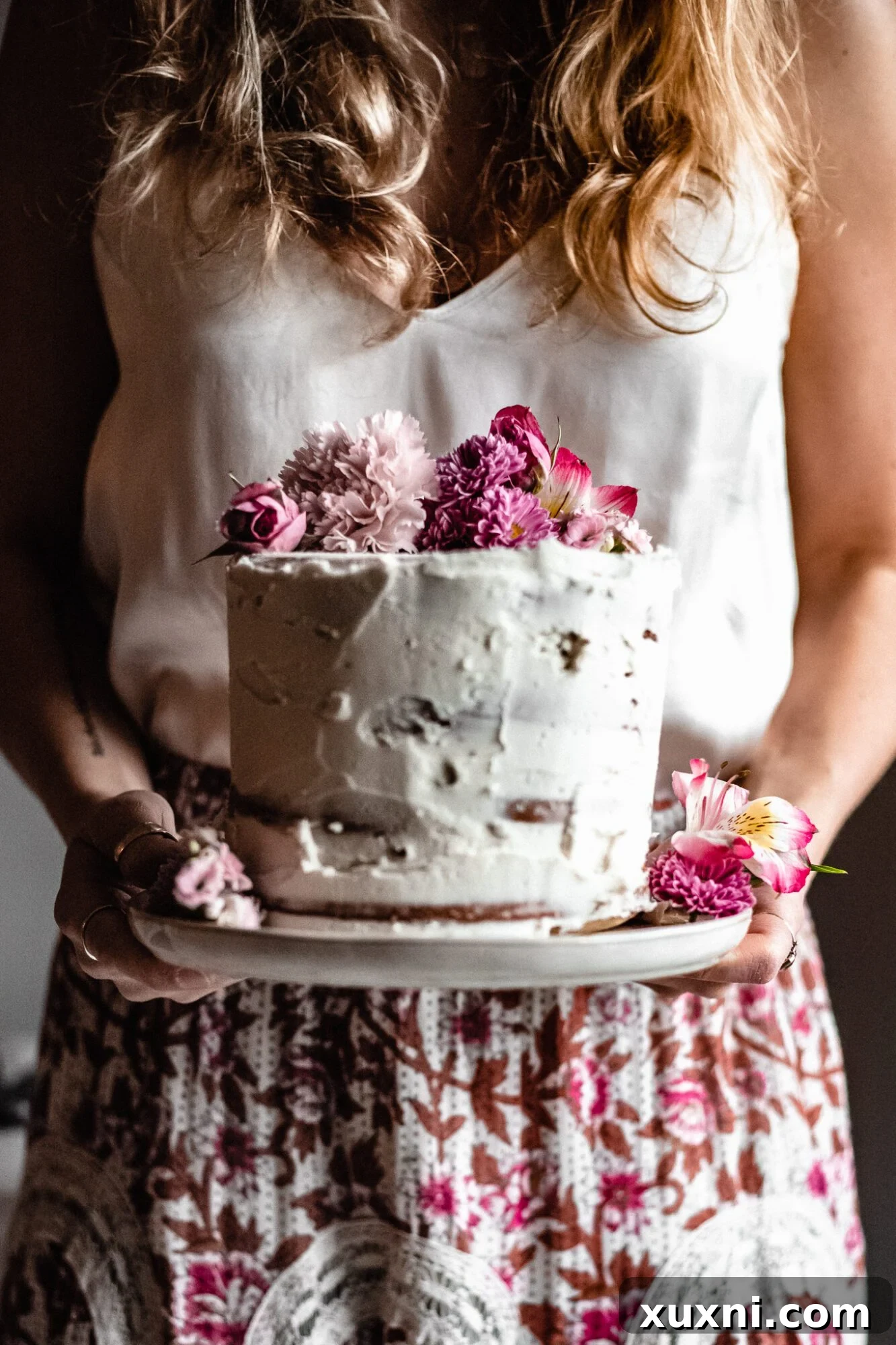 Hands holding a slice of vegan pastel layer cake, showcasing the beautiful internal layers and inviting texture.