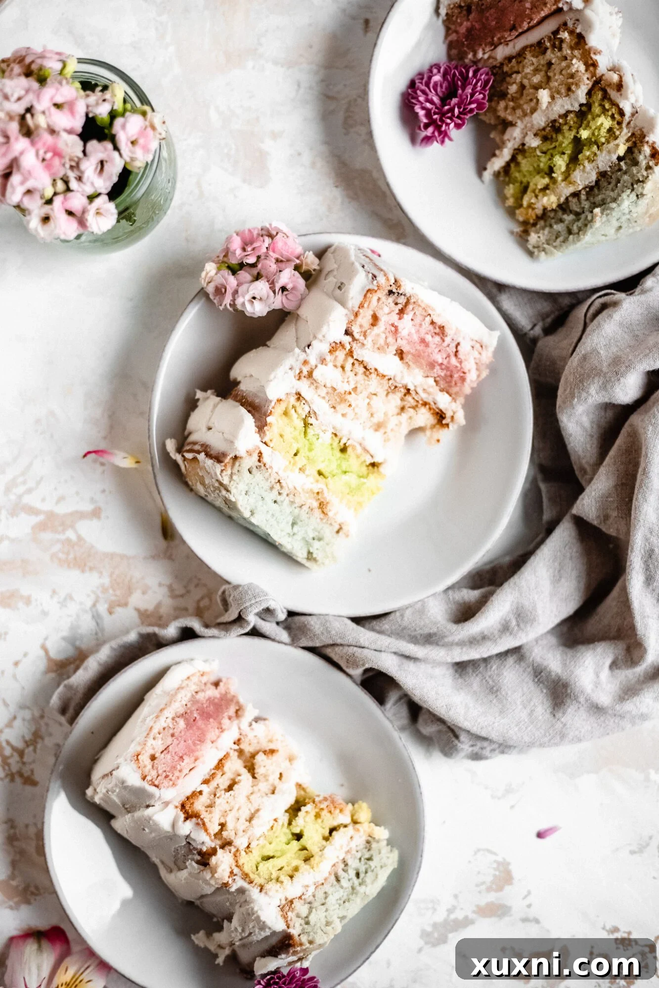 Multiple slices of vegan pastel layer cake arranged artfully, showing off their interior colors.