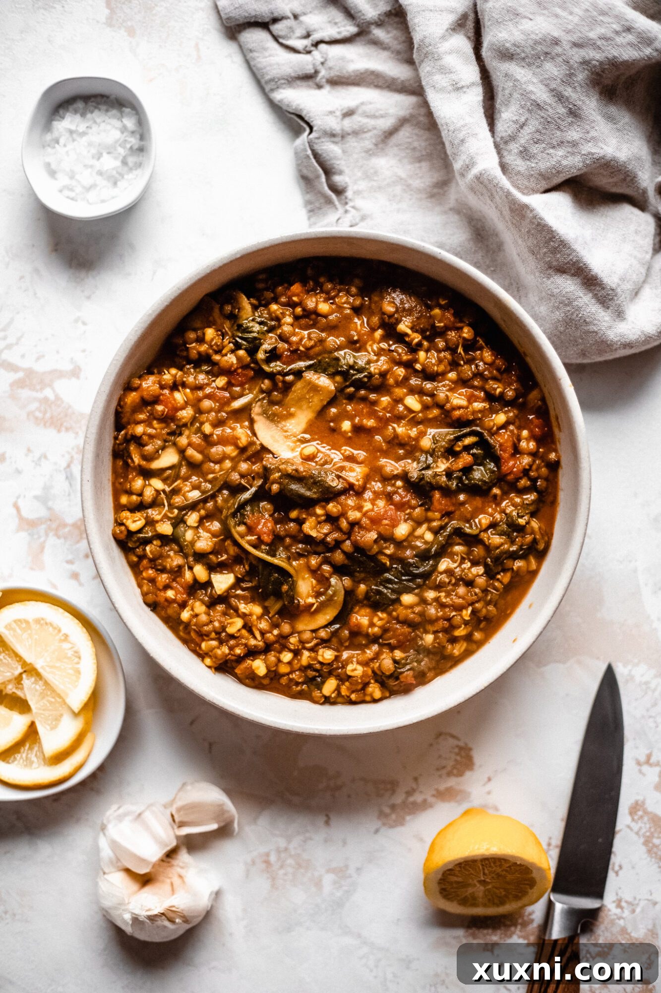 A rustic bowl filled with hearty vegan lentil soup, garnished with fresh parsley.
