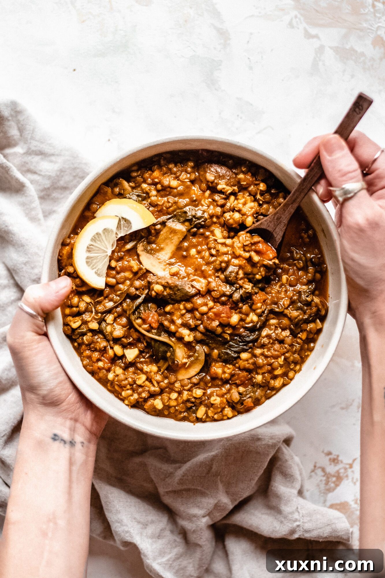 A hand holding a spoon filled with delicious vegan lentil soup, ready to be eaten.