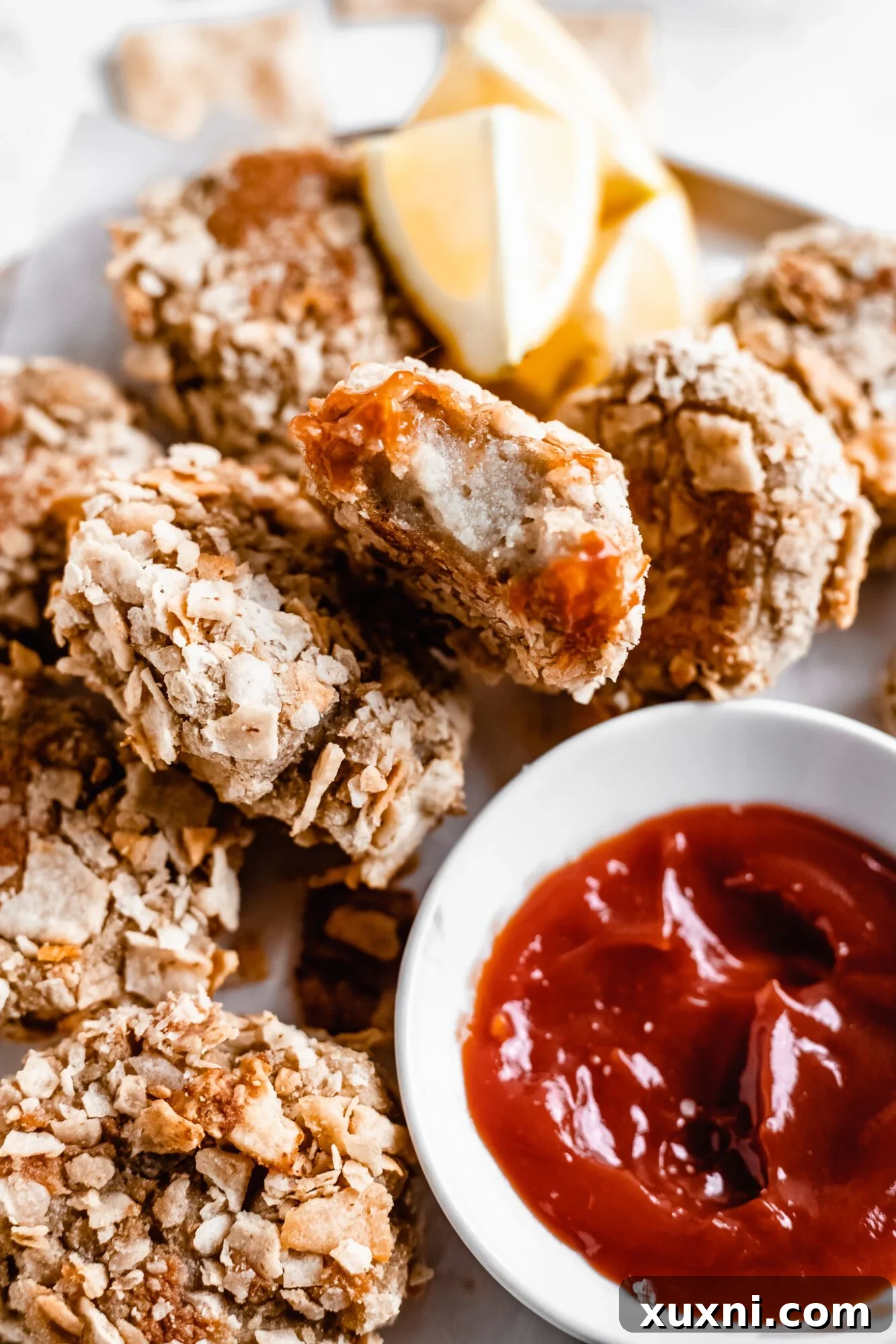 A single, perfectly browned vegan cauliflower nugget resting on a white plate, highlighting its crunchy exterior and golden hue.
