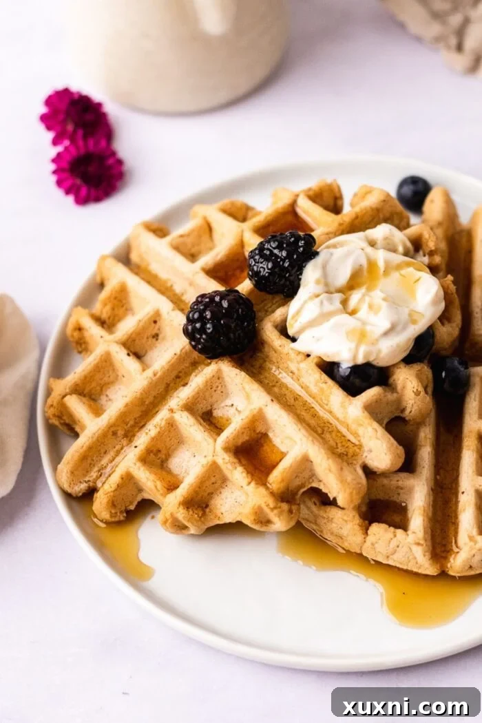 Perfectly golden gluten-free vegan waffles served on a plate with fresh berries and maple syrup, ready for a delicious breakfast.