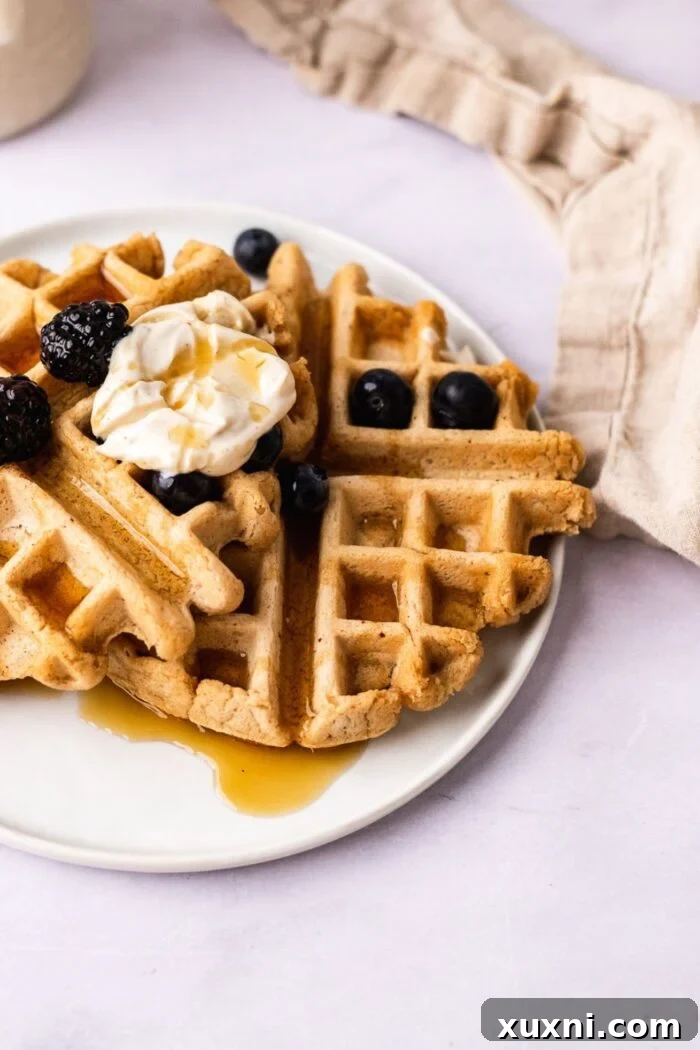 A beautifully plated stack of gluten-free vegan waffles, adorned with fresh berries and ready to be enjoyed.