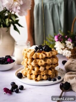 Gluten-free vegan waffles being drizzled with maple syrup.