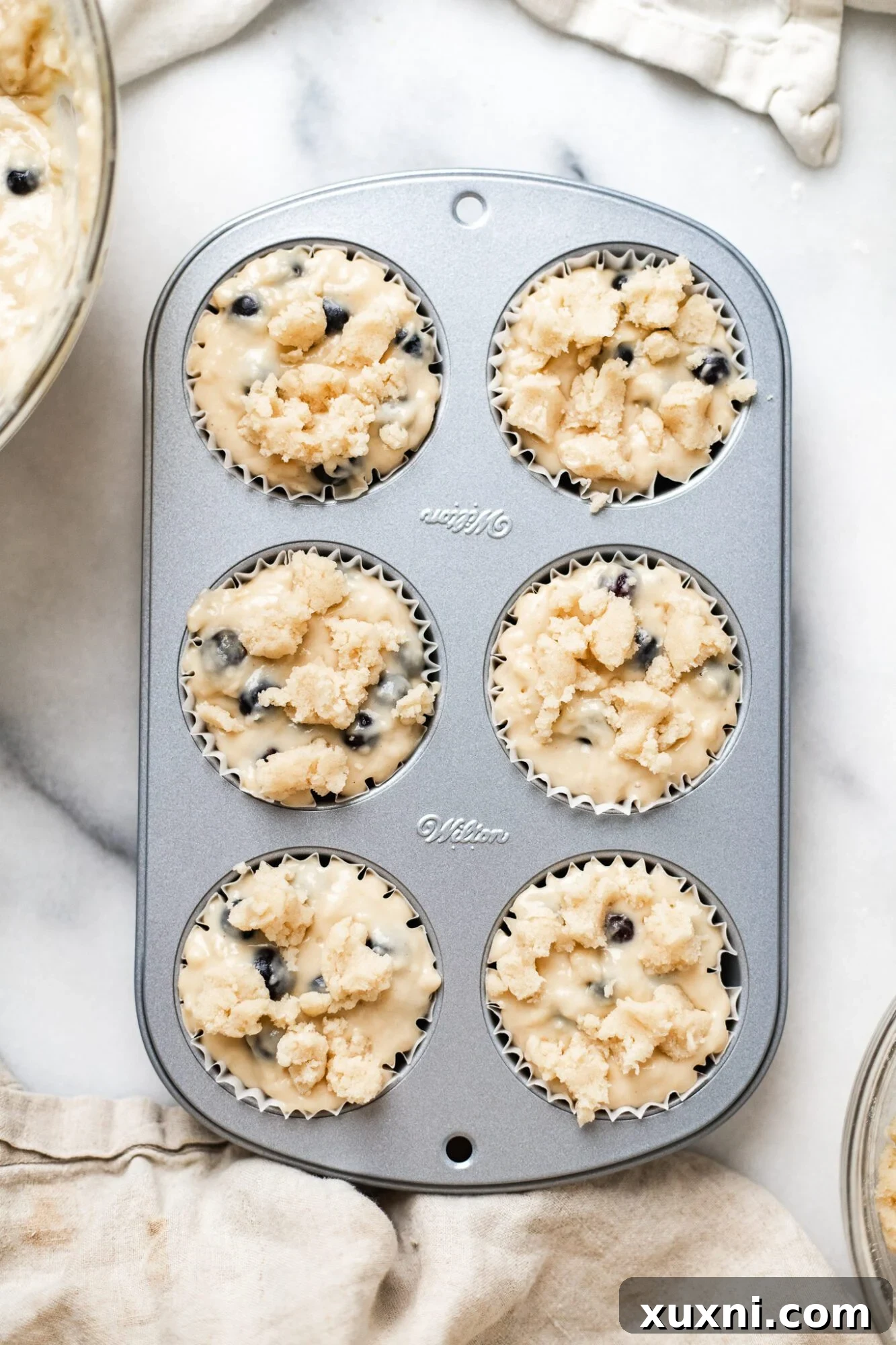 Close-up of vegan blueberry muffin batter with crumble topping before baking.