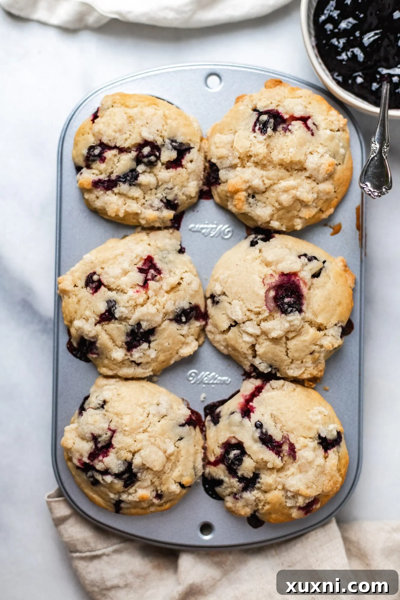 Vegan blueberry muffins baking in the oven, showing the initial rise and crumble topping.