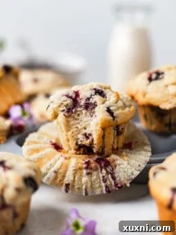 Beautifully baked vegan blueberry muffins with a golden crumble topping, showcasing their fluffy interior and juicy berries, perfect for a bakery-style treat.