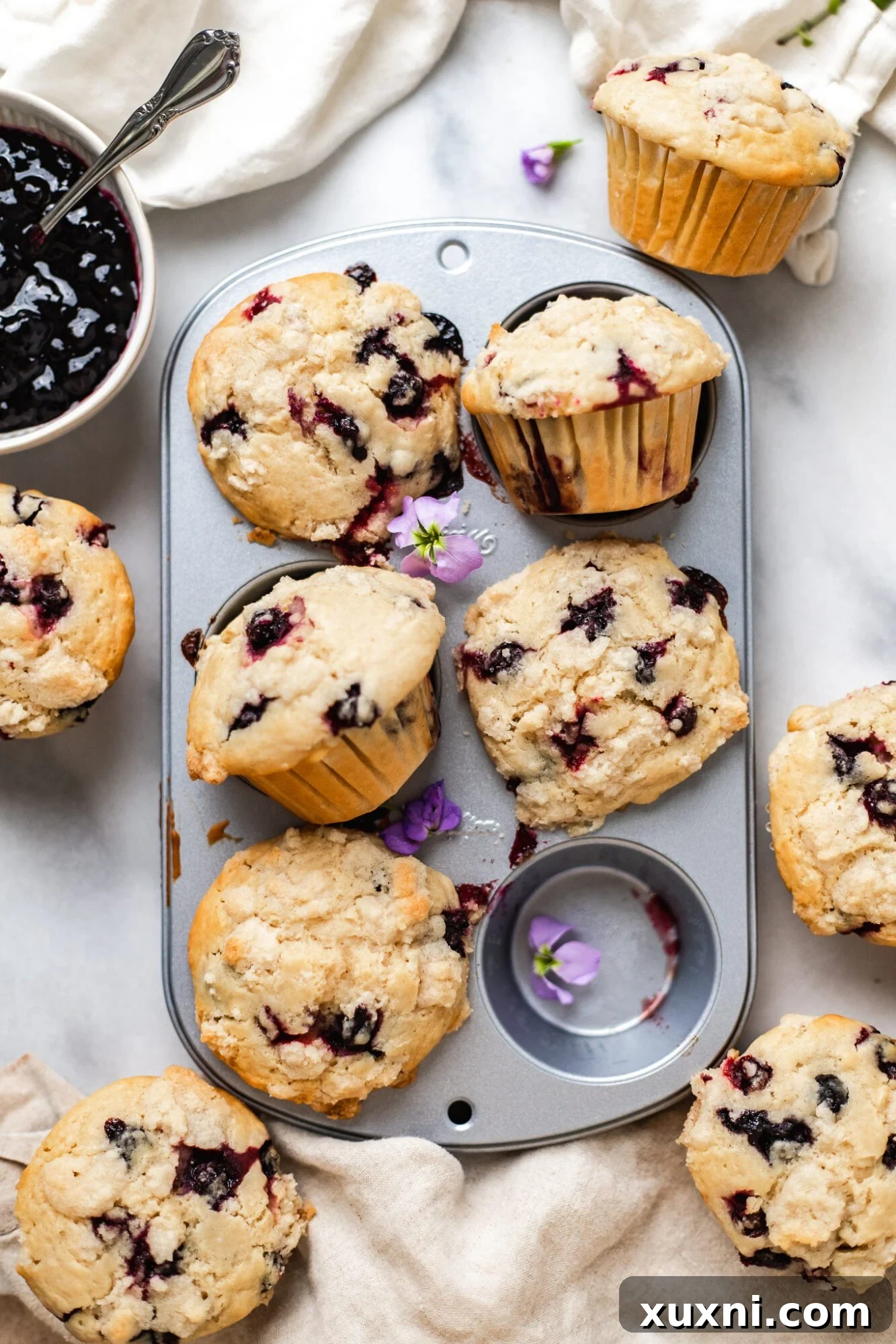 Freshly baked vegan blueberry muffins cooling in a muffin tin, displaying their golden-brown tops.
