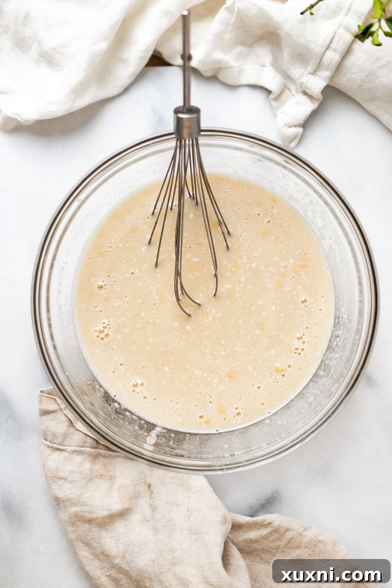 Mixing wet ingredients for vegan blueberry muffin batter in a bowl with a whisk.