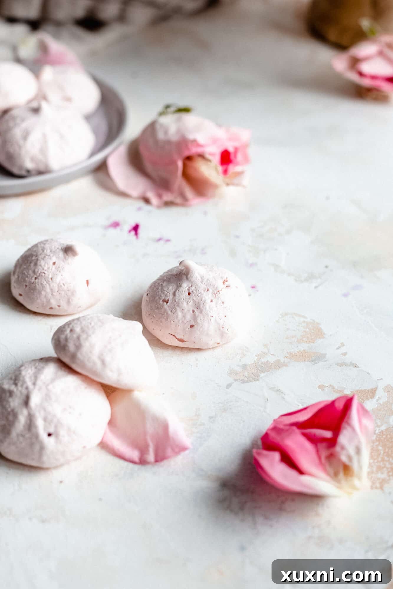 Close-up of vibrant pink vegan meringue cookies with real rose details, highlighting their delicate structure.