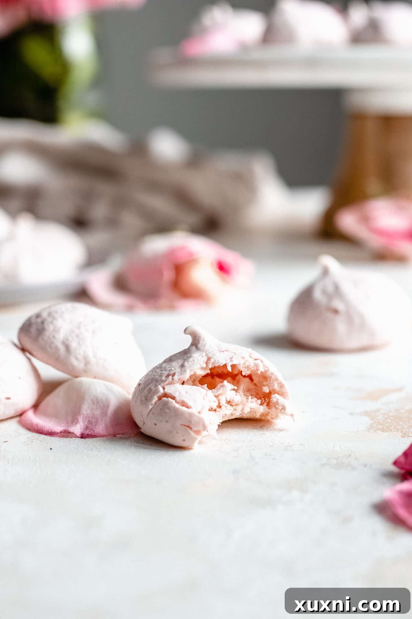 A close-up shot of a partially eaten vegan meringue cookie, revealing its crispy exterior and soft, airy interior.
