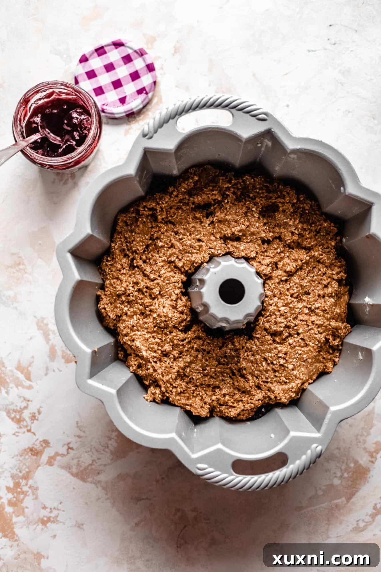 Bundt cake batter expertly layered in the pan with cherry fruit spread.