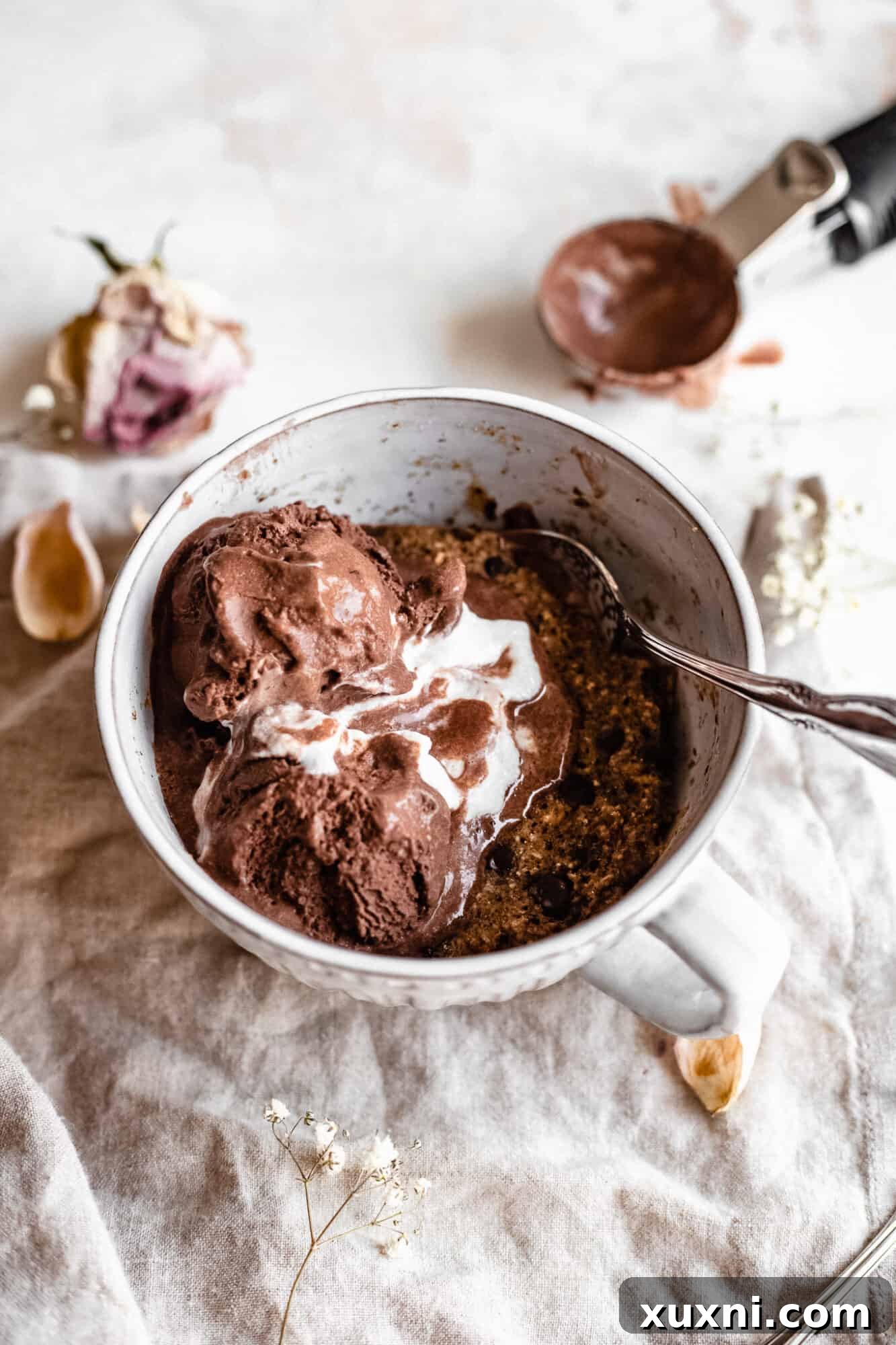 A spoon digging into a freshly made vegan mug cake, showing its soft and warm texture
