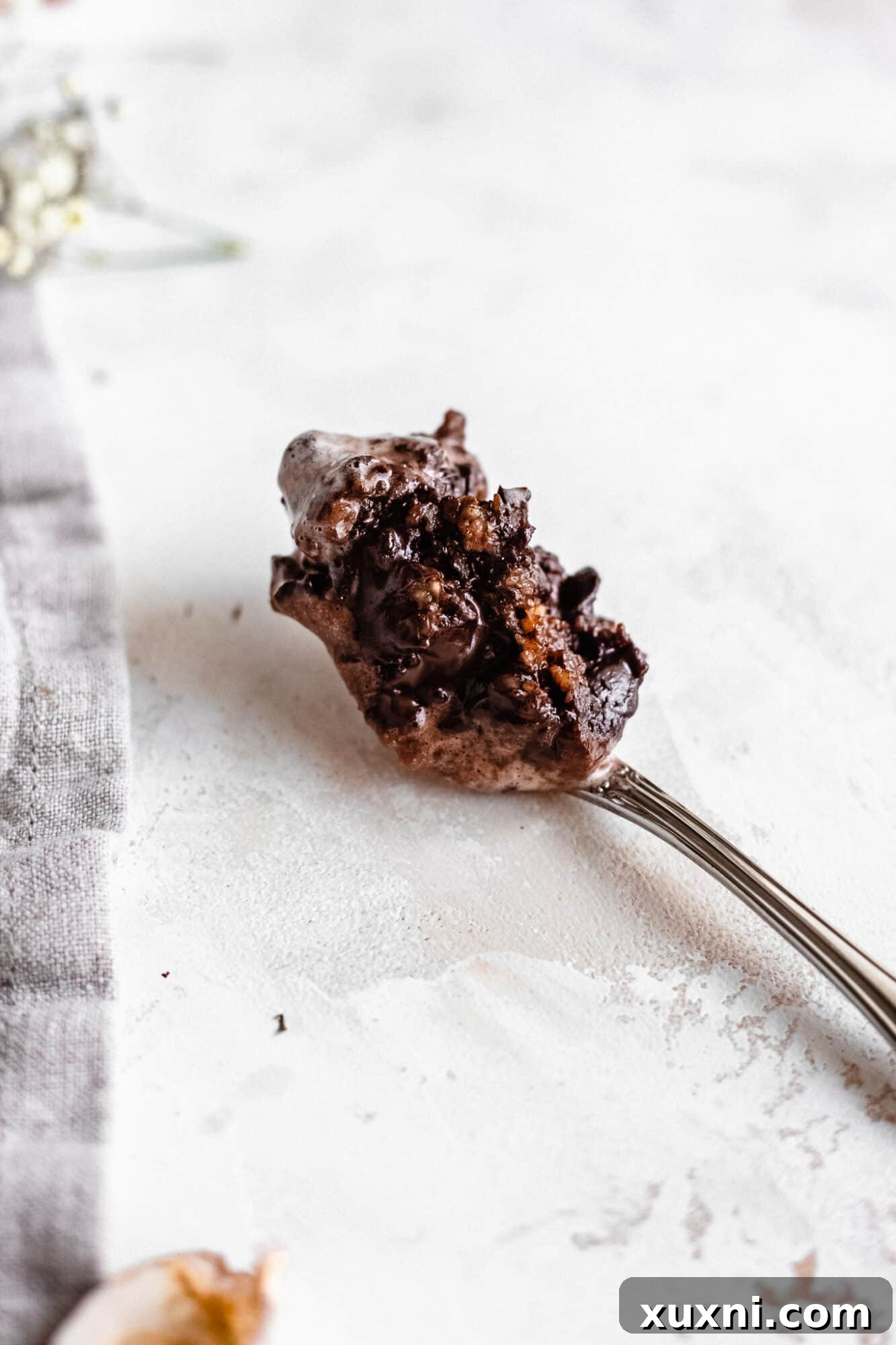 A close-up of a spoon scooping out a portion of the vegan chocolate chip cookie mug cake