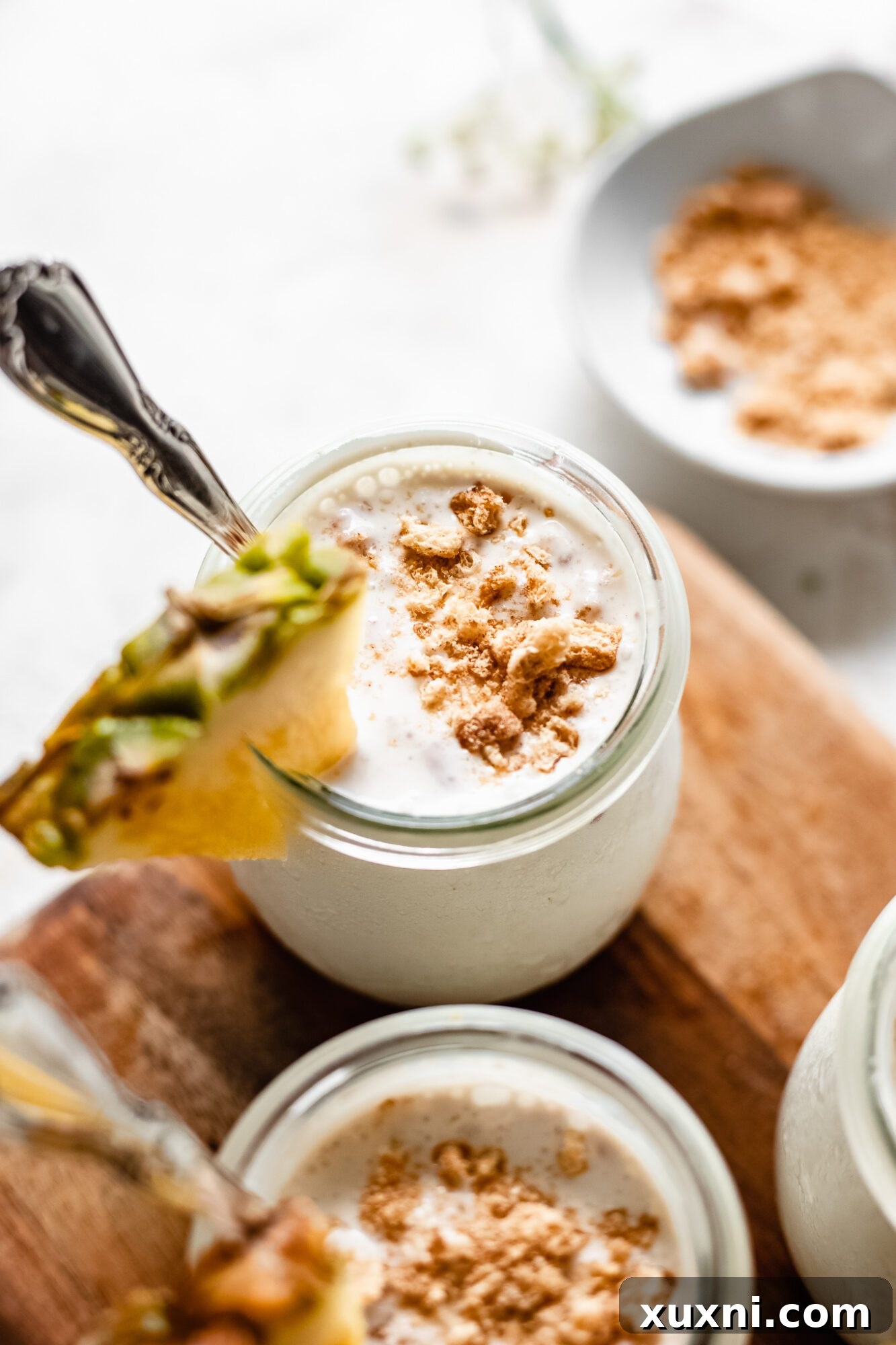 Several jars of creamy vegan pudding arranged on a rustic wooden board, ready for serving or storage.