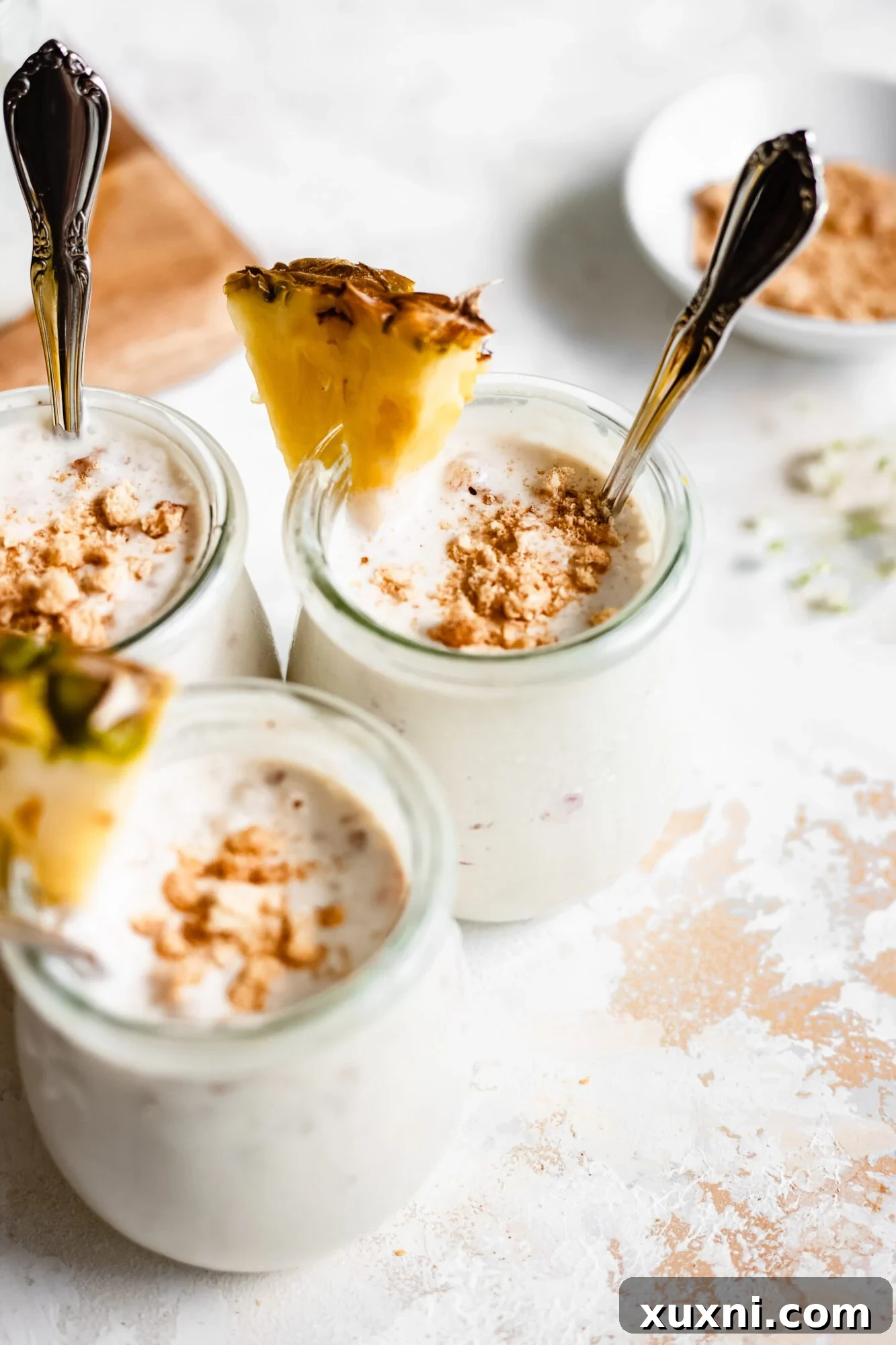 Multiple jars of creamy vegan vanilla pudding, garnished with fresh pineapple, presented invitingly.