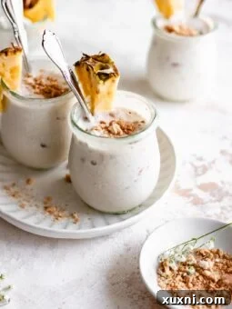 Beautifully arranged jars of vegan coconut pudding with fresh pineapple slices, showcasing a delightful dessert.