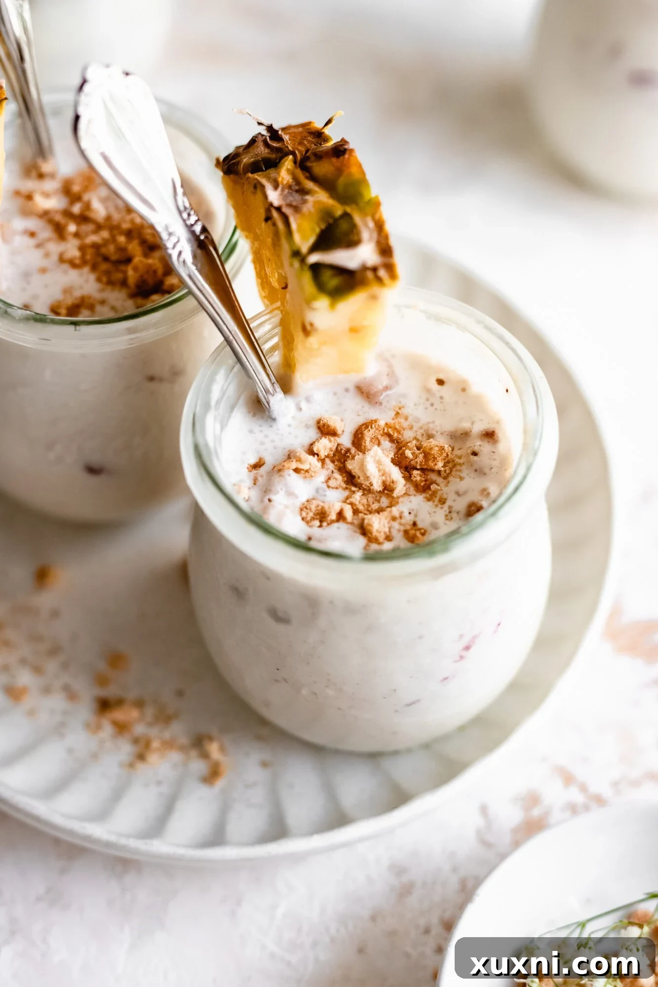 Close-up of a jar filled with creamy vegan vanilla pudding, topped with vibrant pineapple chunks, ready to be enjoyed.