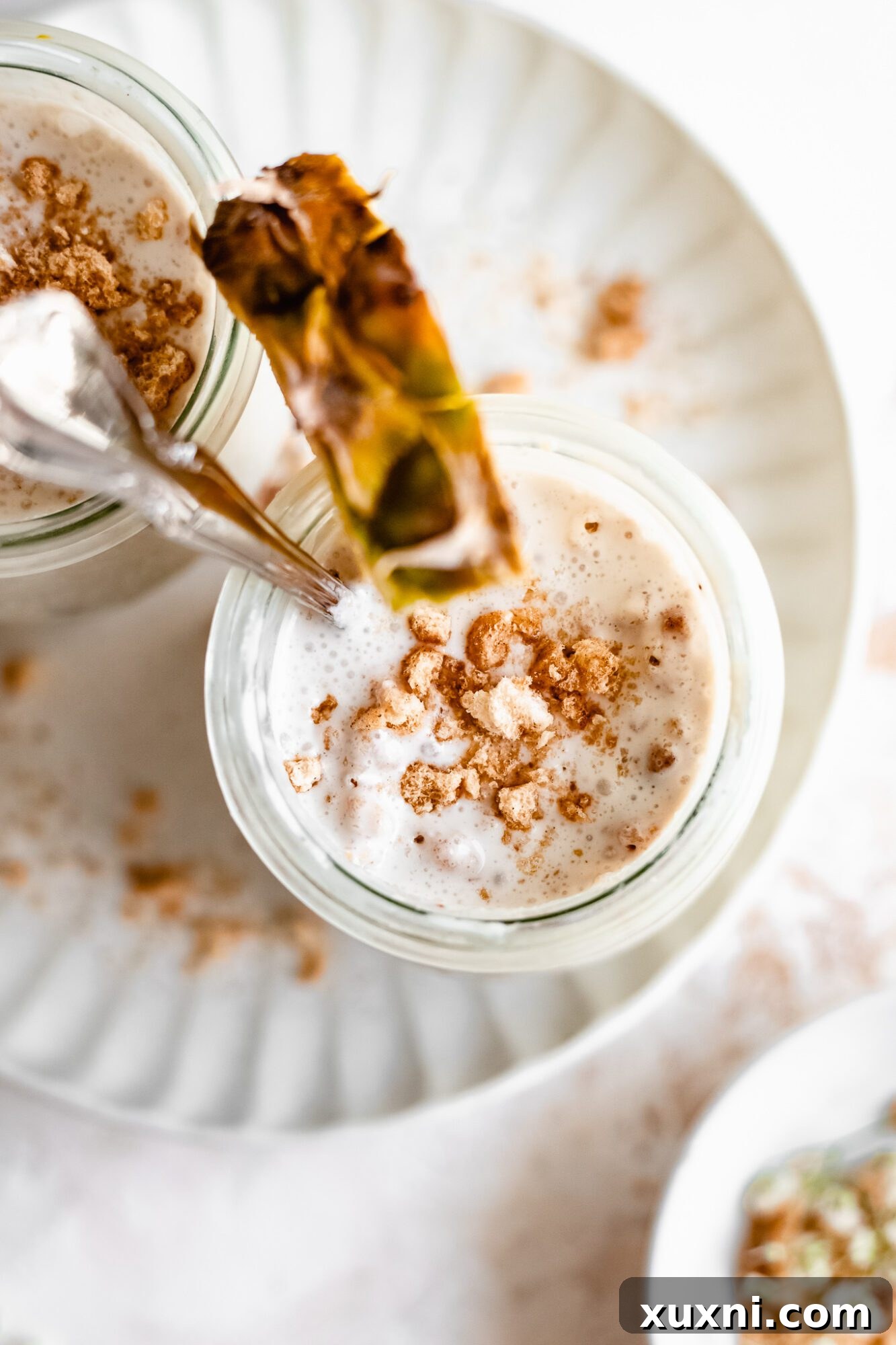 A single jar of exquisite vegan vanilla pudding, artfully garnished with a fresh pineapple slice, inviting a taste of tropical indulgence.
