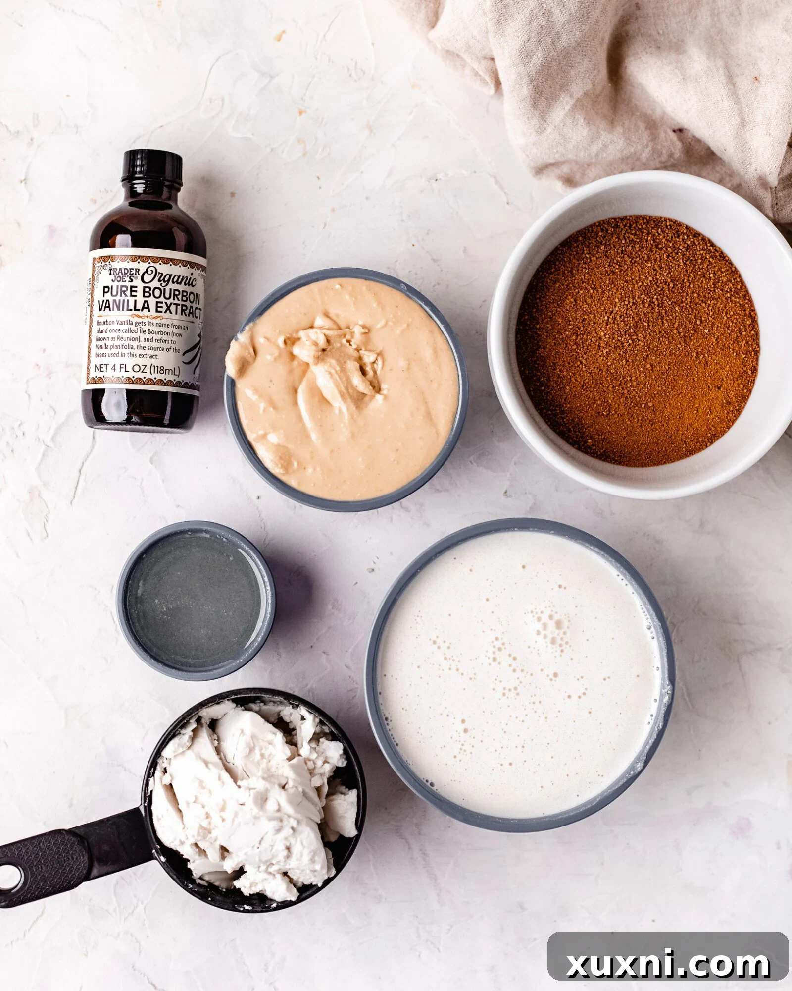 A collection of ingredients for vegan ice cream: cashew milk, coconut cream, cashew butter, vanilla extract, coconut oil, and coconut sugar.