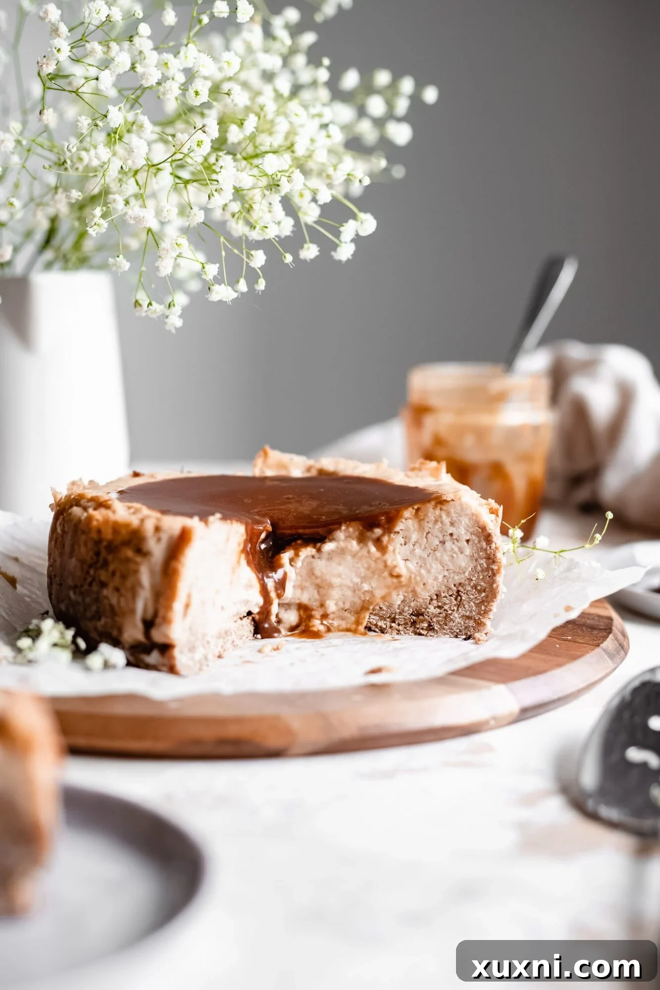 sliced baked vegan vanilla cheesecake with caramel sauce on wooden board