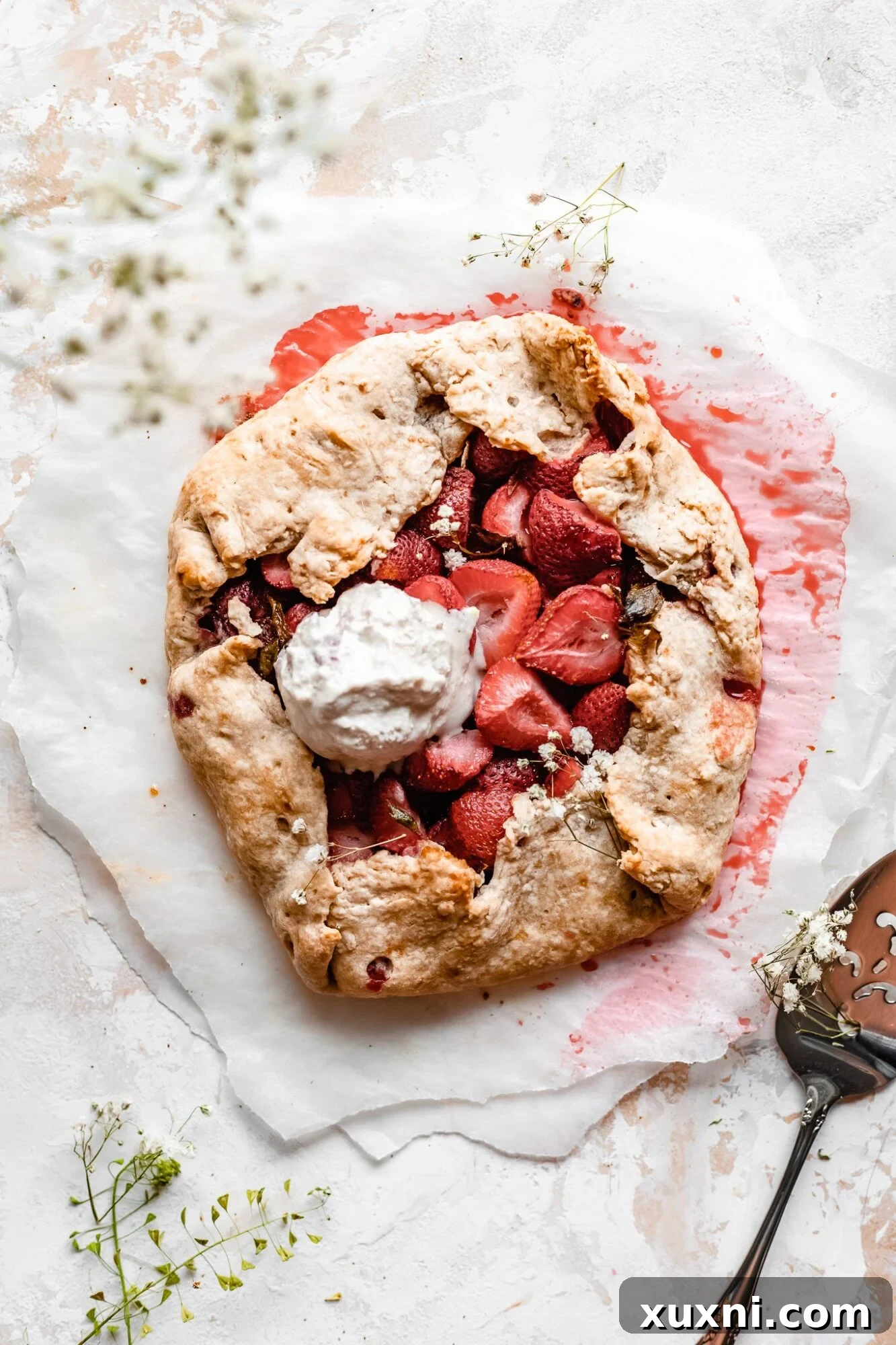 Rustic strawberry galette topped with a scoop of vegan vanilla ice cream, ready to be served