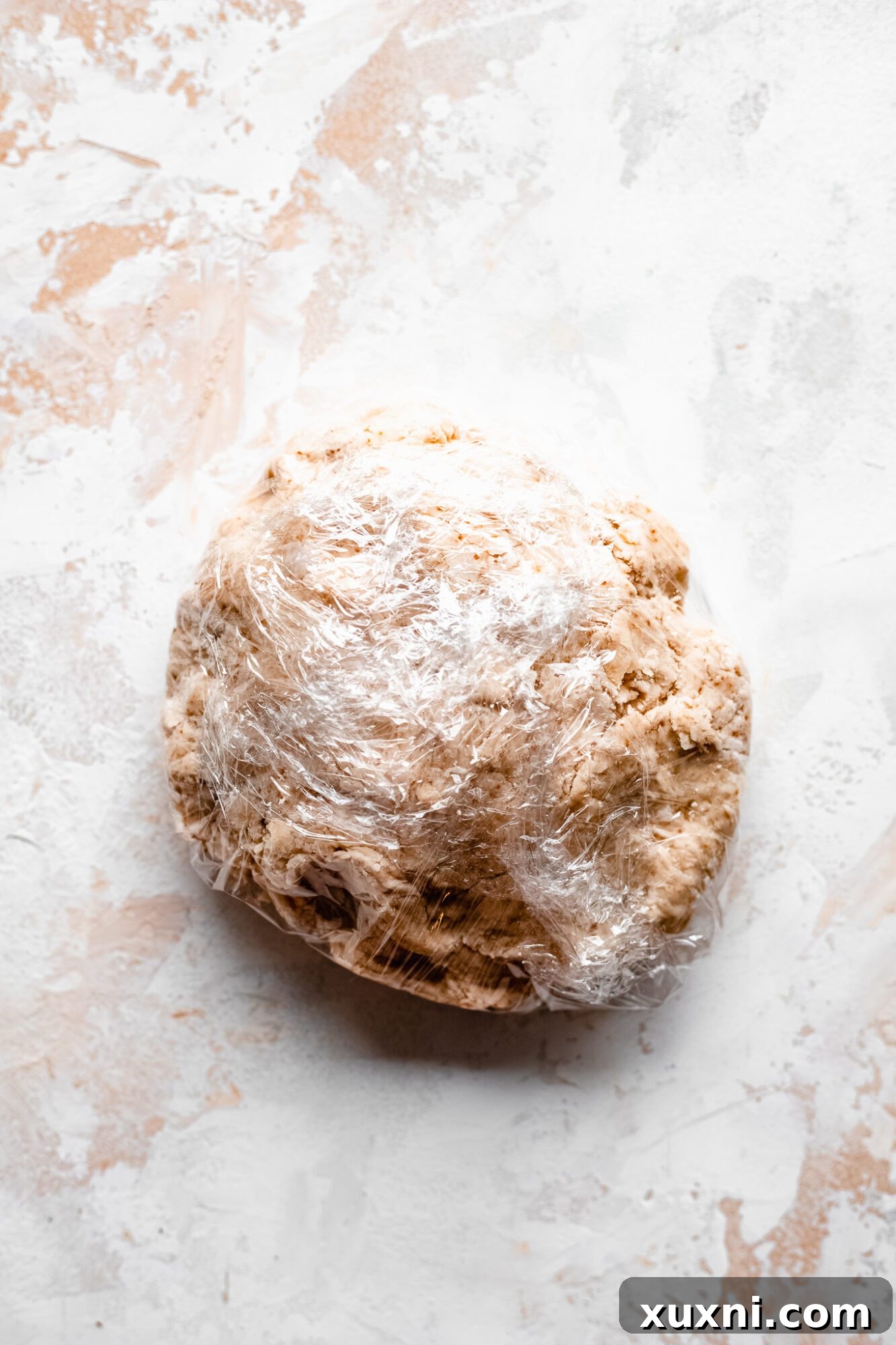 Circular dough disk wrapped in plastic wrap, chilling in the refrigerator