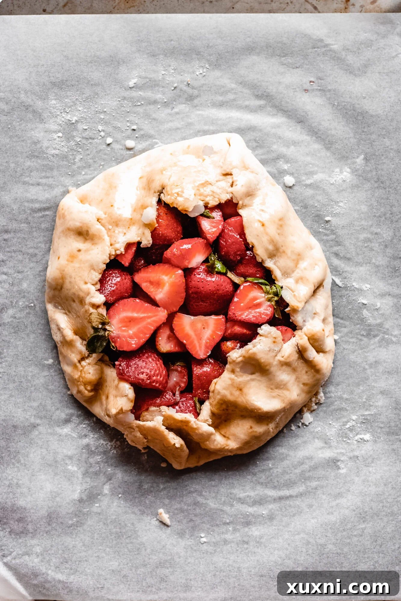 Unbaked strawberry galette sitting on a baking sheet, ready for the oven