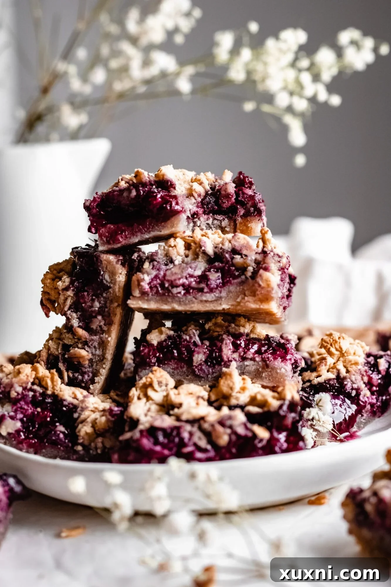 Stack of freshly baked healthy blueberry crumble bars, showcasing a golden crust and vibrant blueberry filling.
