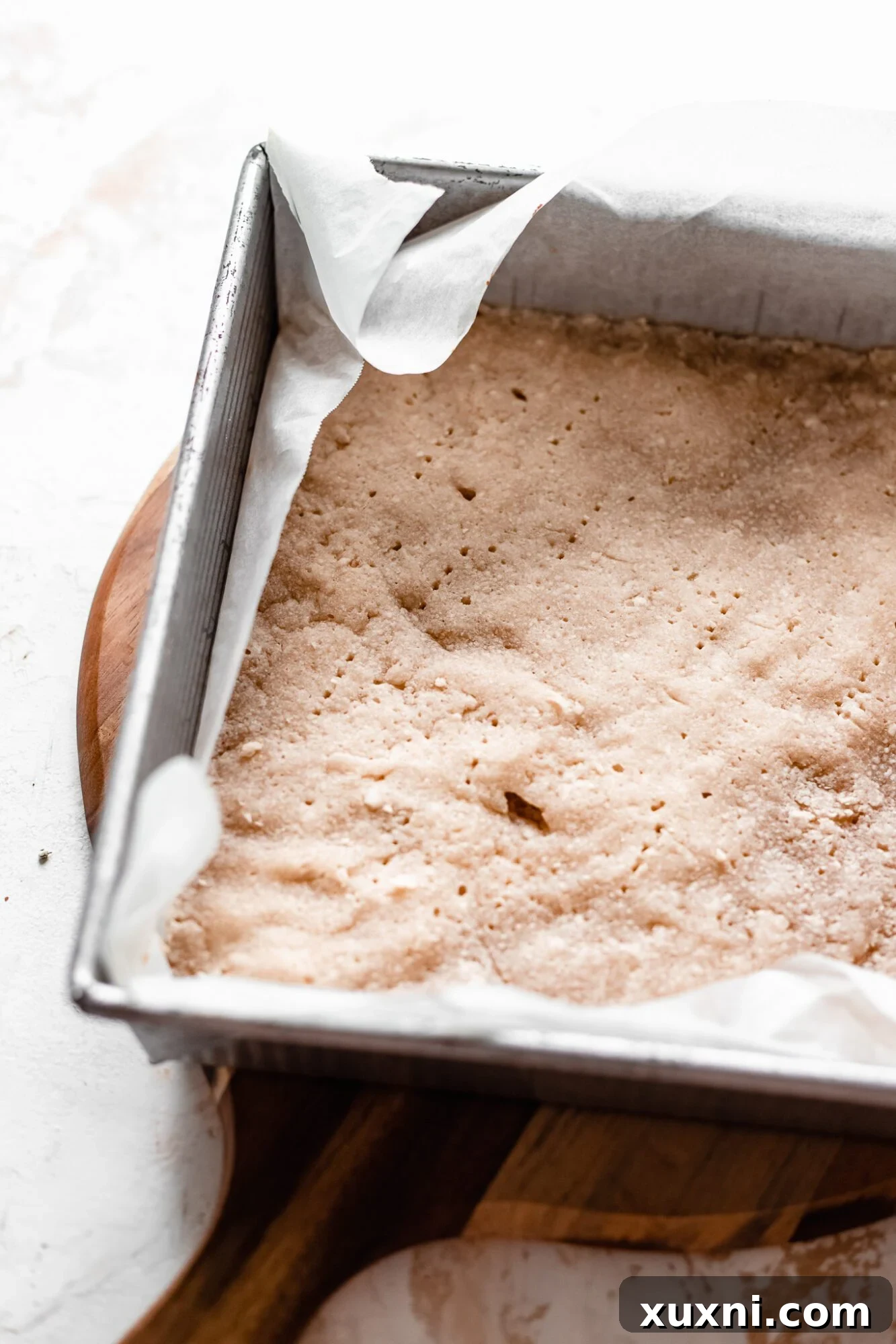 A golden, par-baked pie crust waiting in a baking pan, ready for filling.