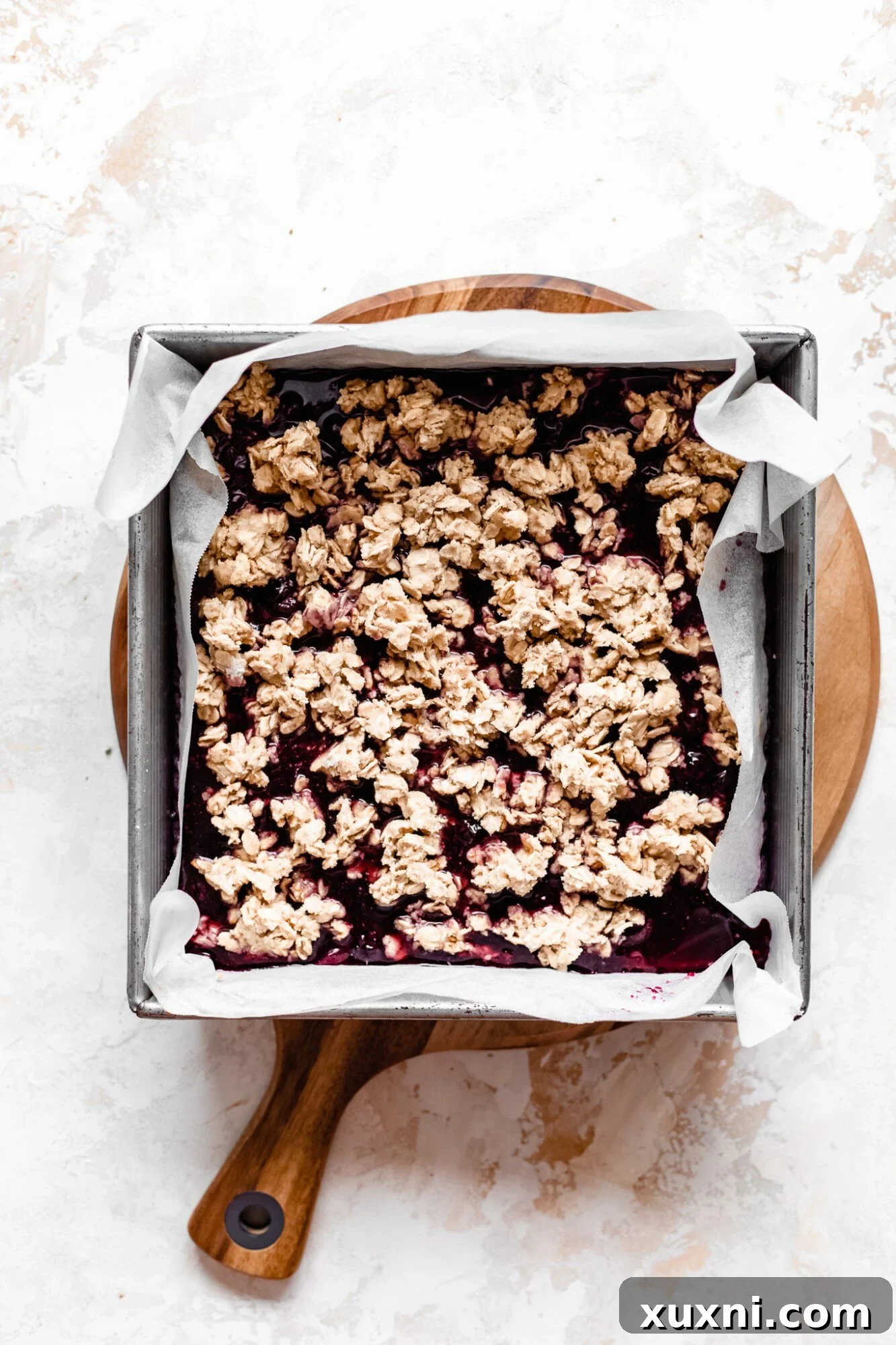 Unbaked blueberry crumble bars showing the crust, filling, and topping layers before going into the oven.