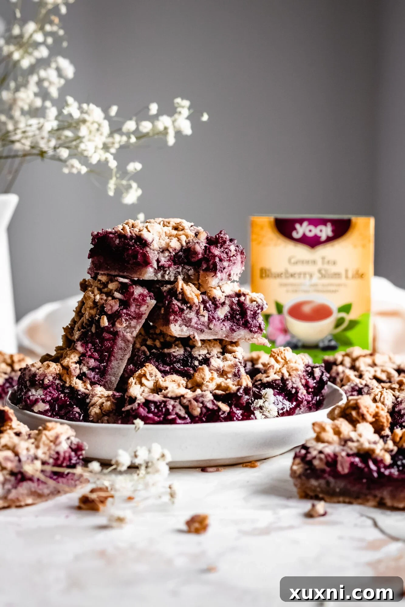 Stacked vegan blueberry bars with a box of Yogi Tea in the background, illustrating the tea infusion.