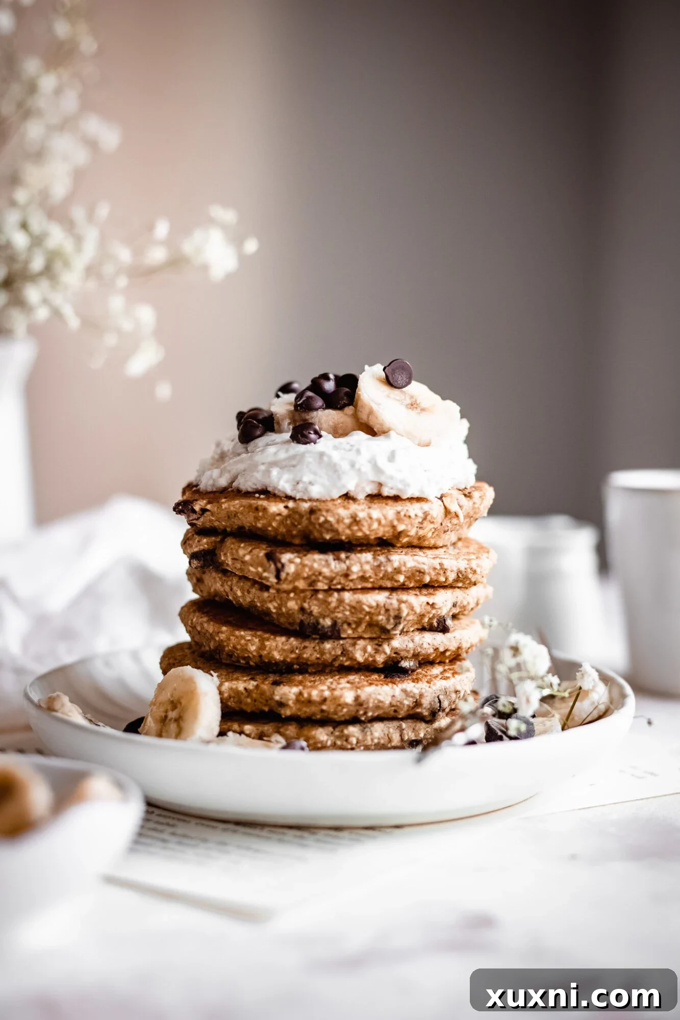 stack of oatmeal pancakes with coconut whipped cream and chocolate chips